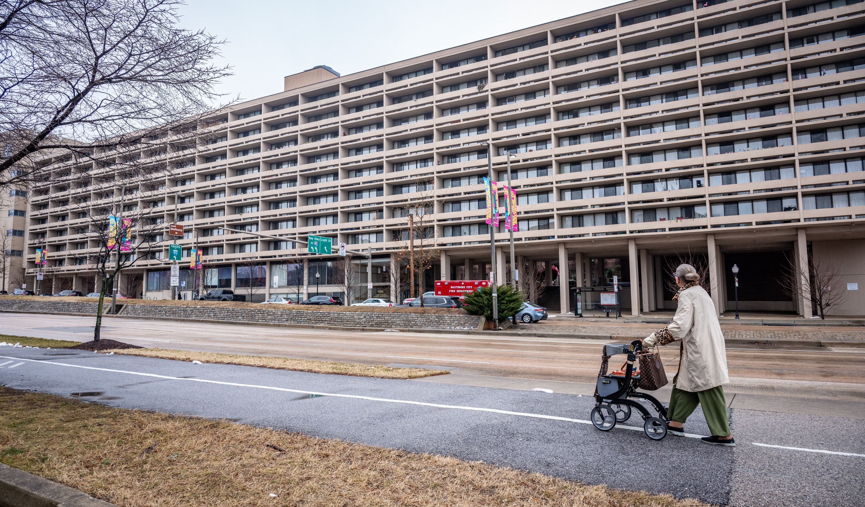Mary Theresa Weil, 77, walks past the Christ Church Harbor Apartments on Light Street where she has lived happily for eight years. Last summer she accidentally left a battery pack out on a balcony in the heat and a small fire caused some damage. Now, the building won’t renew her lease.