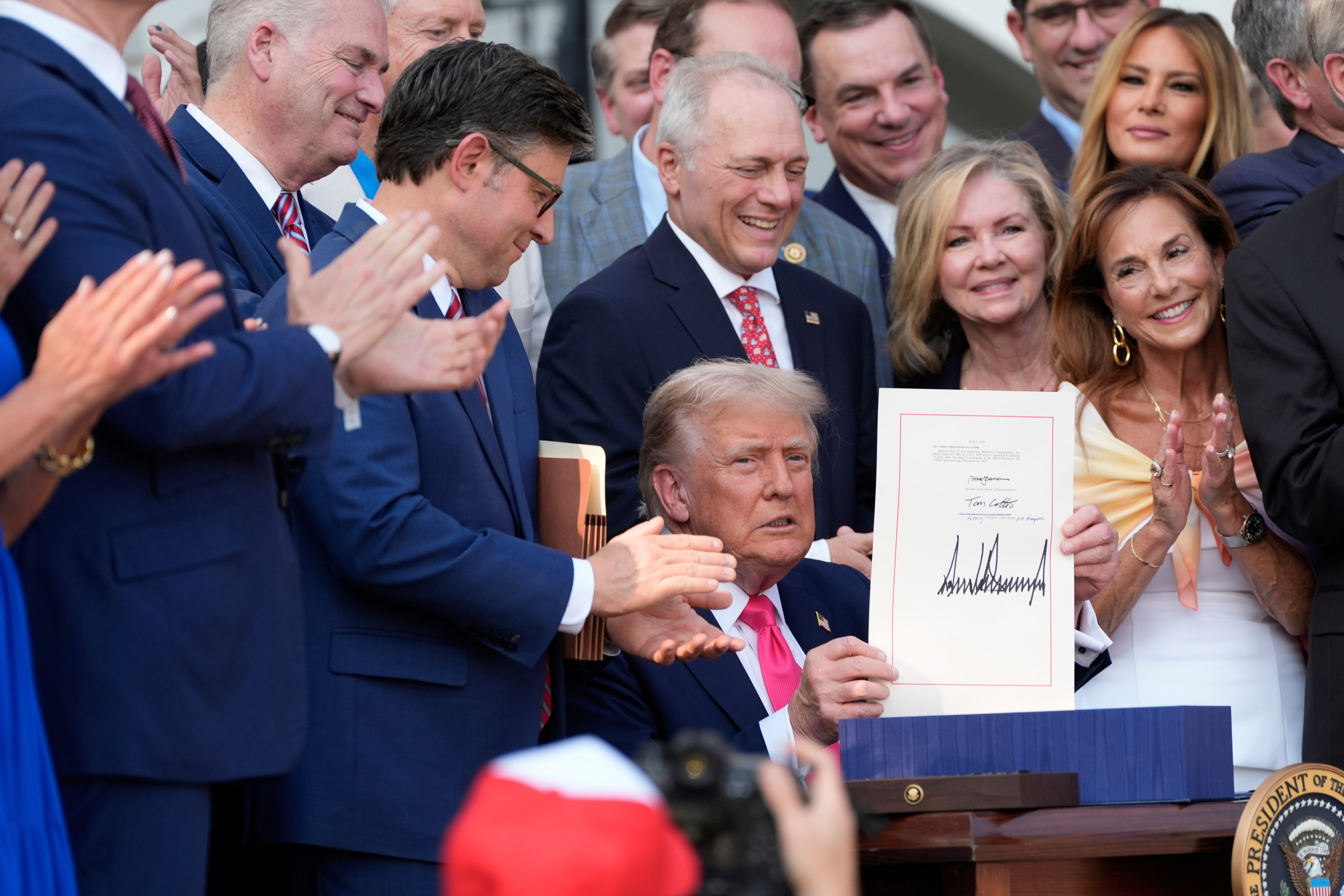 President Donald Trump holds up his signed signature bill of tax breaks and spending cuts at the White House in Washington, Friday, July 4, 2025.