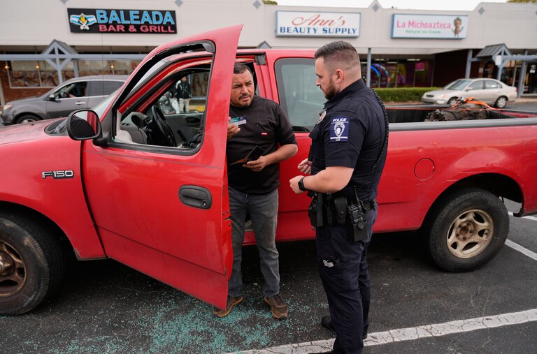 Willy Aceituno, left, makes a police report with Charlotte-Mecklenburg Police Department officer N. Sherill, after U.S. Customs and Border Protection officers broke his window during an enforcement operation, Saturday, Nov. 15, 2025, in Charlotte, N.C. (AP Photo/Erik Verduzco)