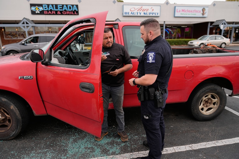 Willy Aceituno, left, makes a police report with Charlotte-Mecklenburg Police Department officer N. Sherill, after U.S. Customs and Border Protection officers broke his window during an enforcement operation, Saturday, Nov. 15, 2025, in Charlotte, N.C. (AP Photo/Erik Verduzco)