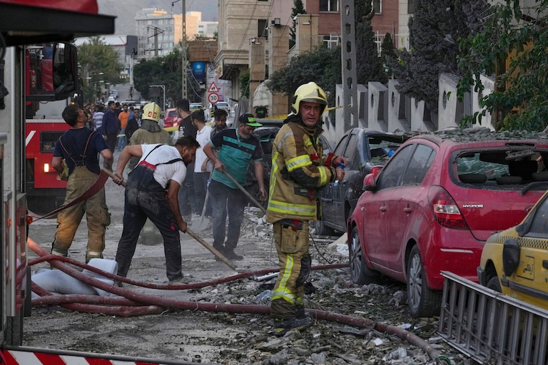 Firefighters and people clean up the scene of an explosion at a residence compound after Israeli attacks in Tehran, Friday, June 13, 2025. (AP Photo/Vahid Salemi)