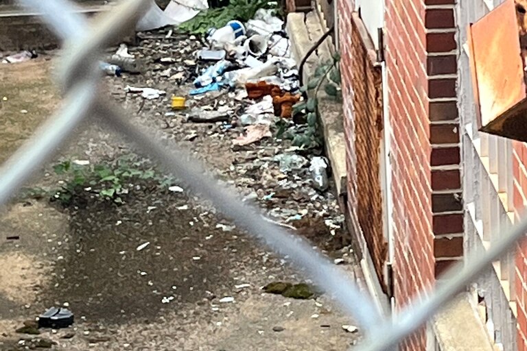 Trash outside the sexual health clinic building at 1515 W North Avenue is seen through a chain-link gate.