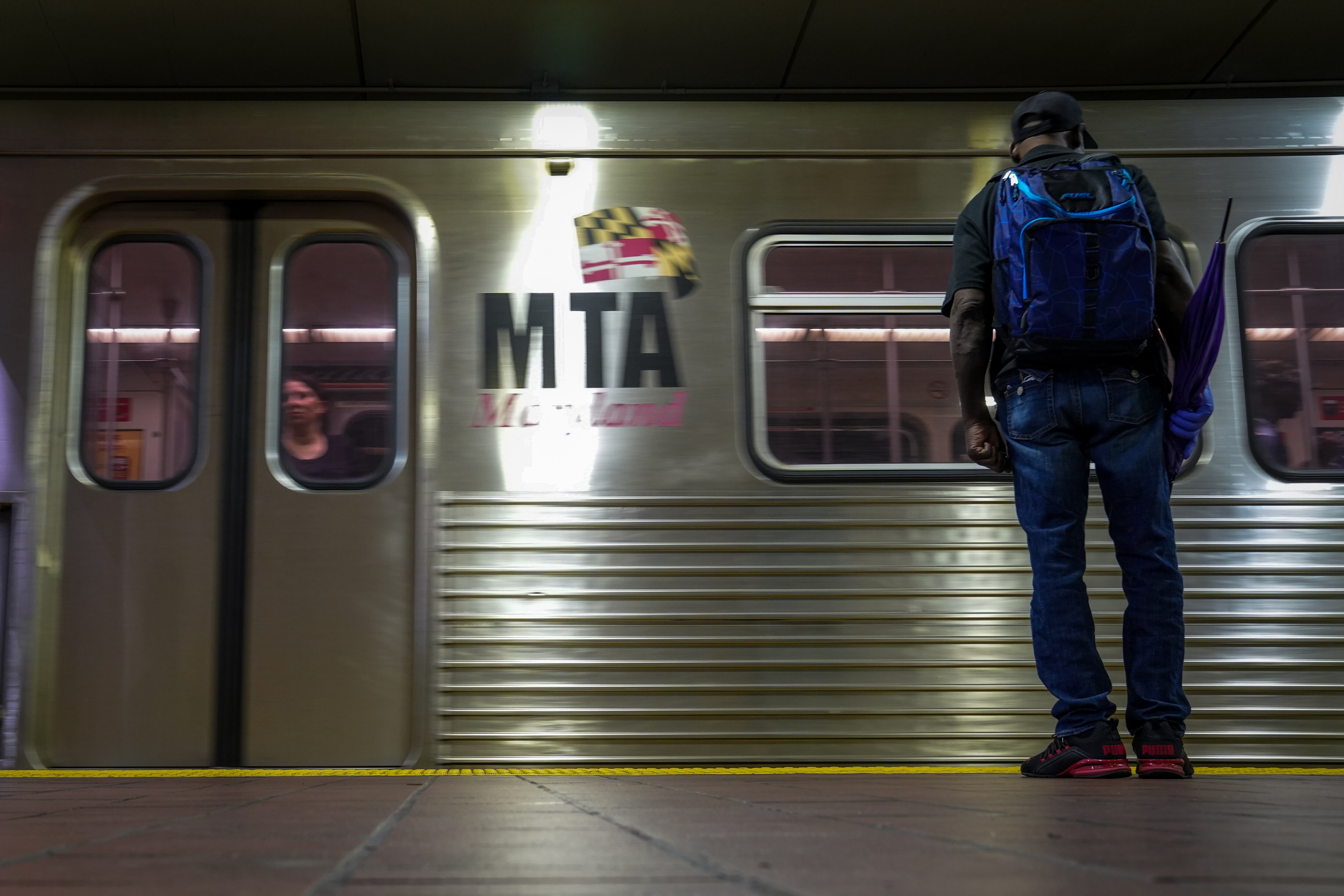 Interior of Charles Center Station as a subway train arrives and a rider waits to board on 8/11/22.