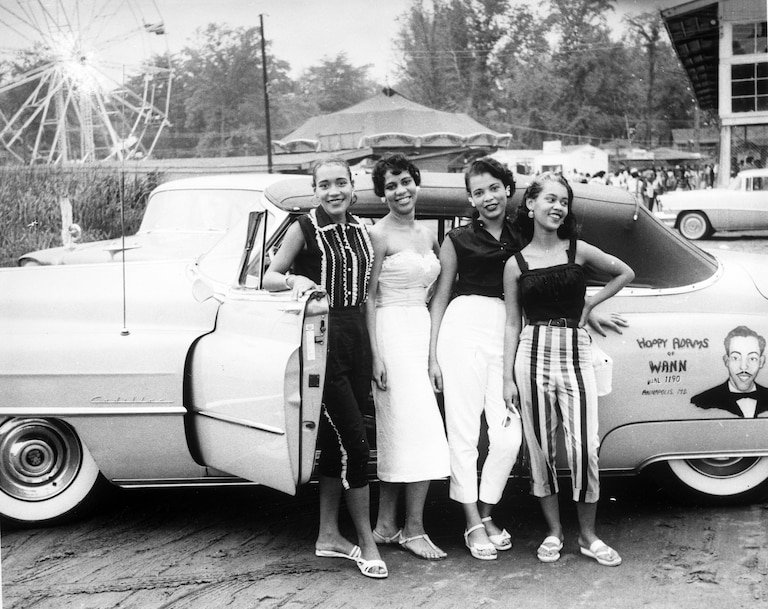 Four women standing in front of car parked at Carr’s Beach in the 1950s/early 1960s.