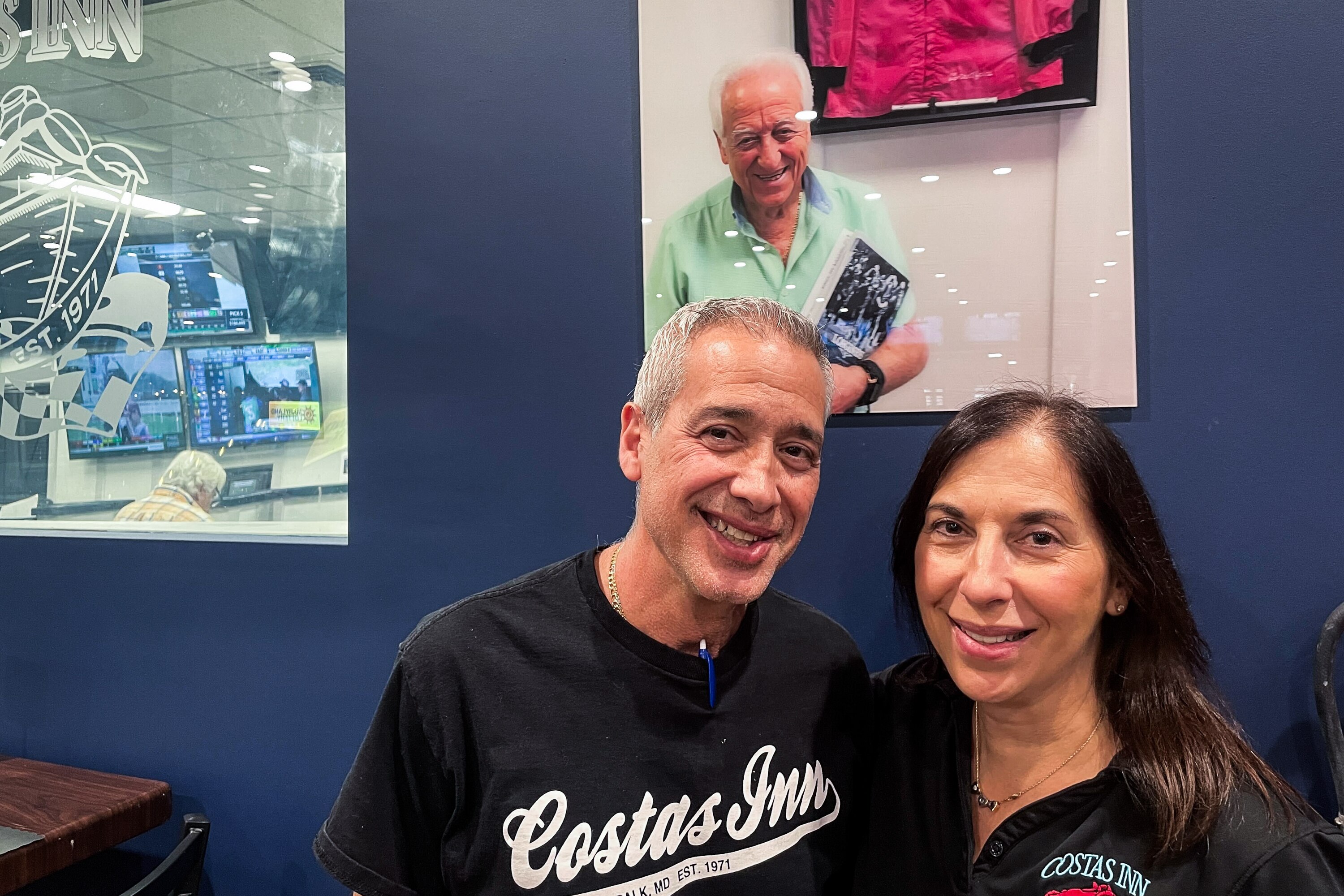 Siblings Pete Triantafilos and Christine Lambros-Shifflett stand below a portrait of their late father, Costas Triantafilos, that hangs in the new Costas Inn at the Maryland State Fairgrounds.