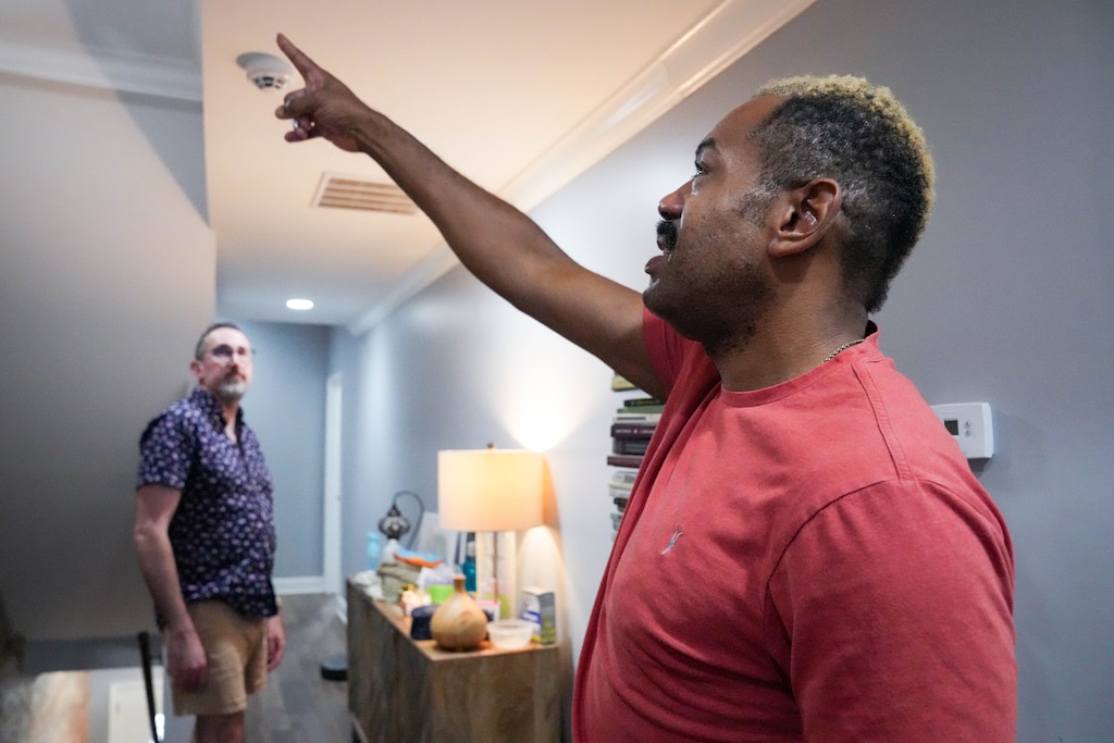 Brian Dawson, right, points out damage in their ceiling as he gives a house tour with his husband, Topher Bengtson, in their Reservoir Hill home in Baltimore, Md. on Friday, August 22, 2025.
