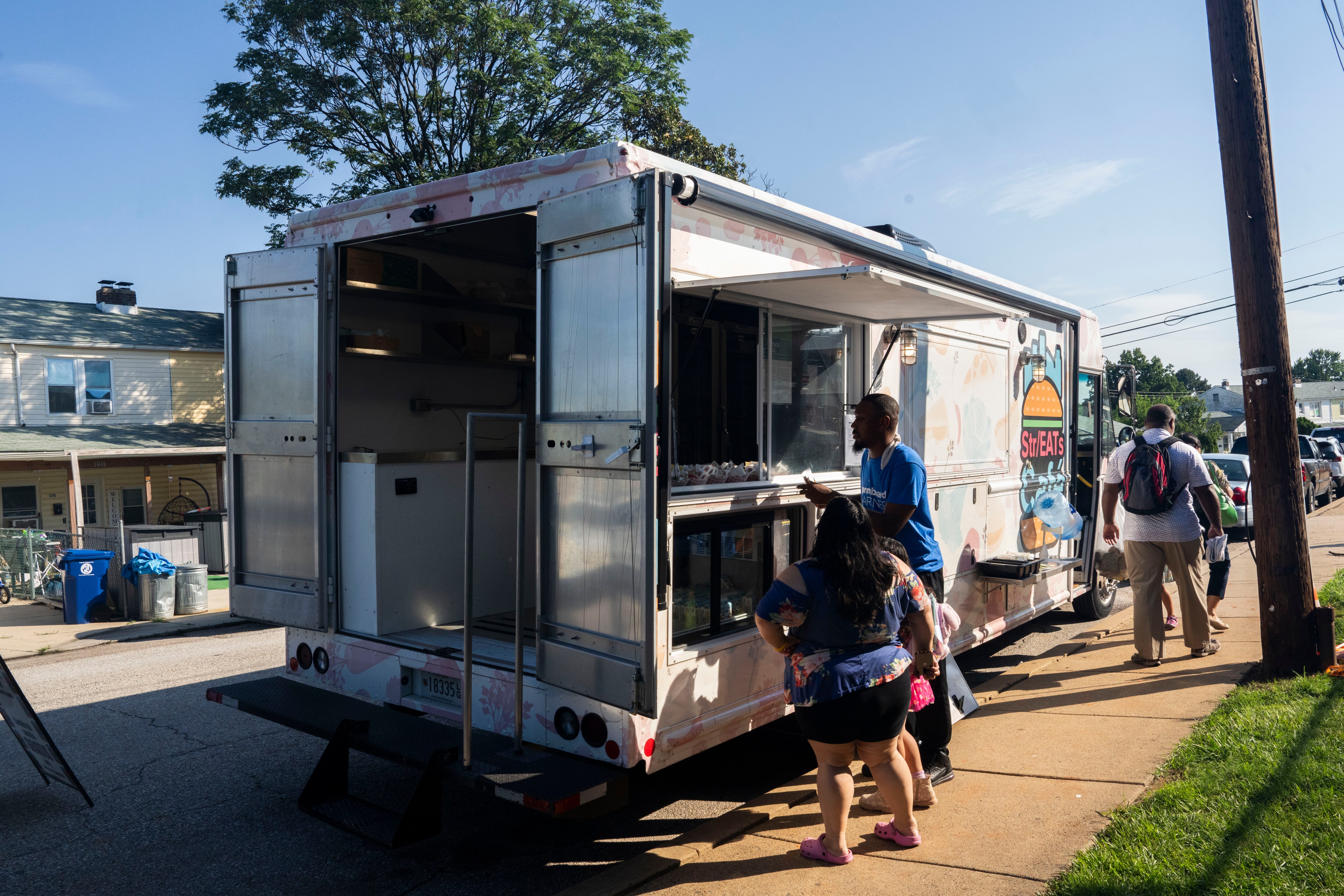 Employees prepare food to be handed out from the Str/EATs Cafe food truck parked outside of Armistead Gardens Elementary/Middle School.