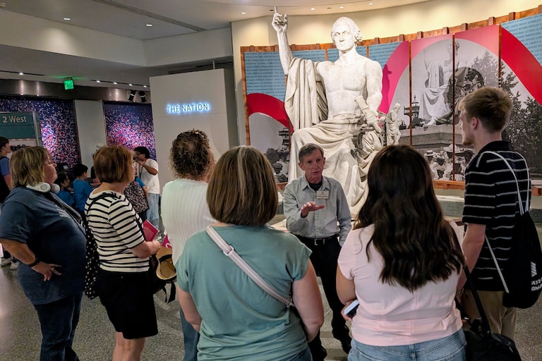 A docent explains why George Washington has no shirt in Horatio Greenough's marble statue of the nation's founder at the National Museum of American History.
