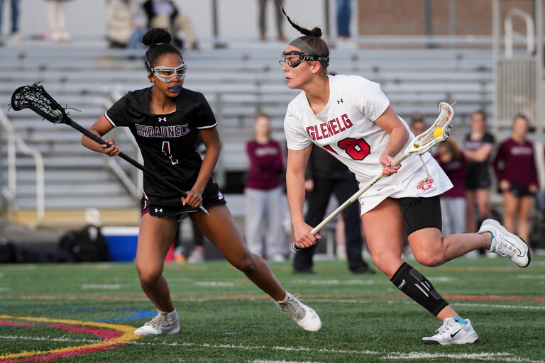 Glenelg’s Isa Torres (18) runs past Broadneck’s Nya Williams (1) in the first half of a girls lacrosse game at Glenelg High School on Tuesday, March 28. Glenelg defeated Broadneck, 11-8.