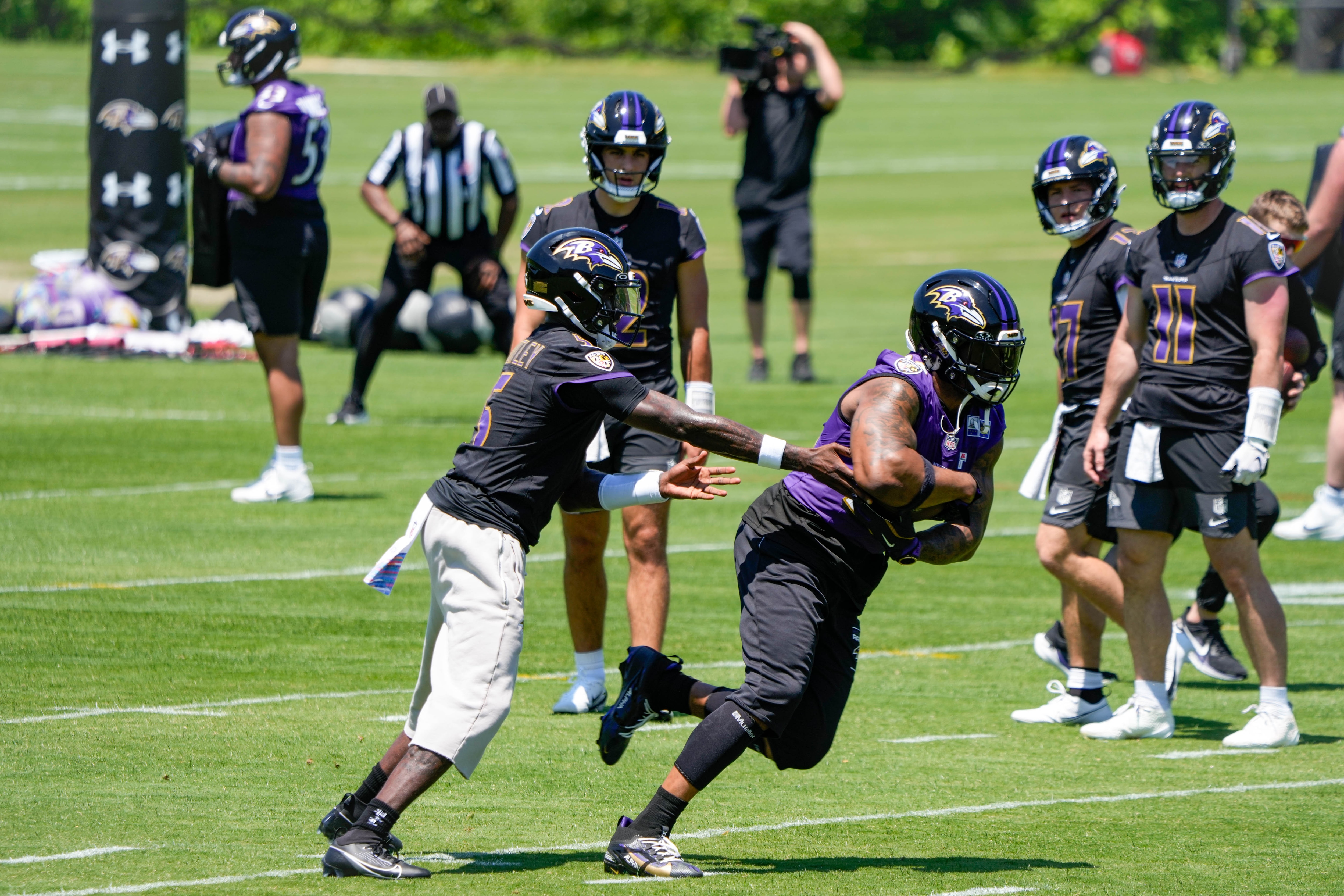 Baltimore Ravens quarterback Tyler Huntley (5) hands the ball off to running back Derrick Henry (22) during organized team activities Tuesday.