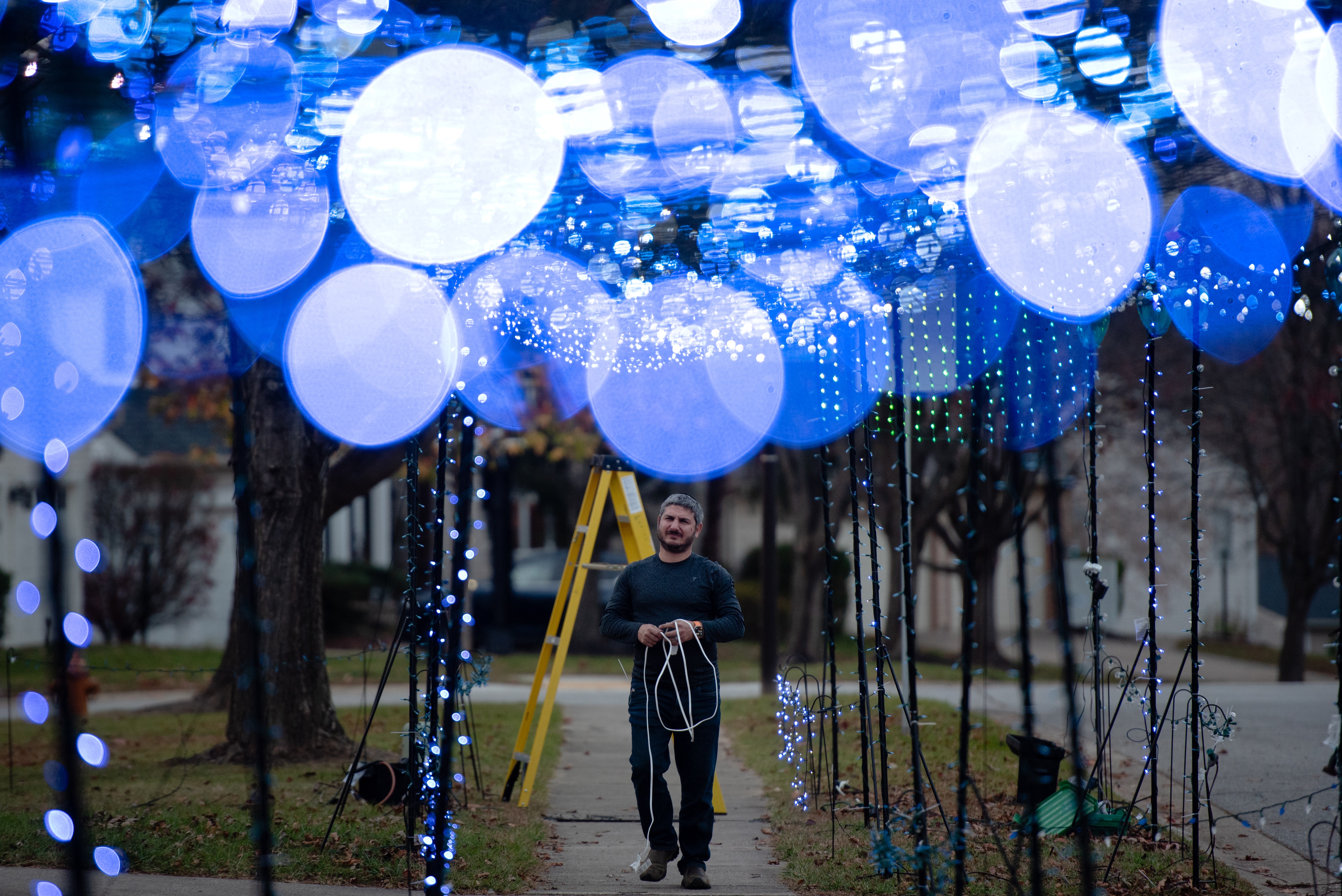 Matt Levine walks under a tunnel of string lights he hung in celebration of the upcoming Hanukkah holiday outside of his Columbia, MD home on November 17th, 2024.