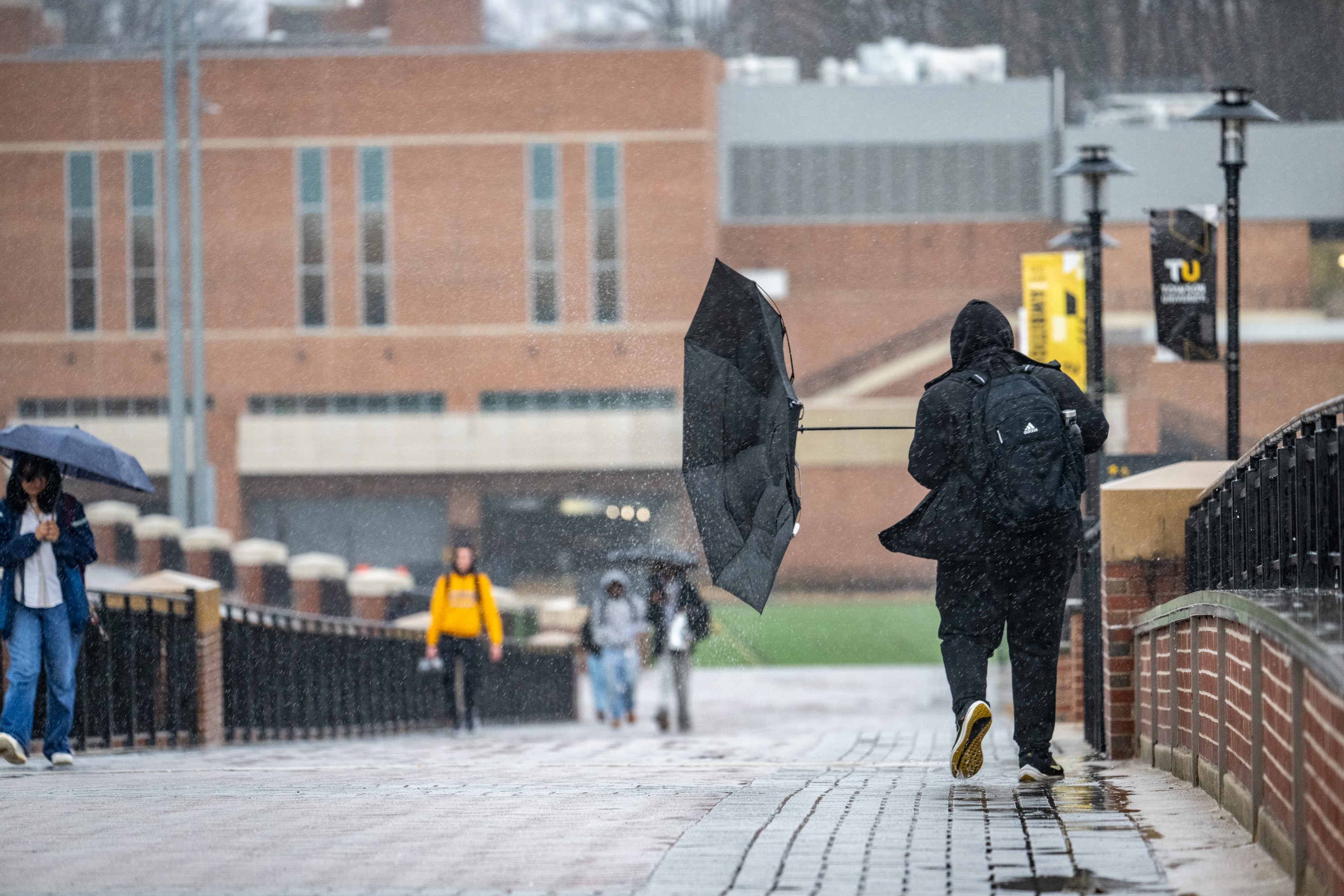A gust of wind grabs a Towson student’s umbrella as students walk between classes in the rain Wednesday afternoon.
