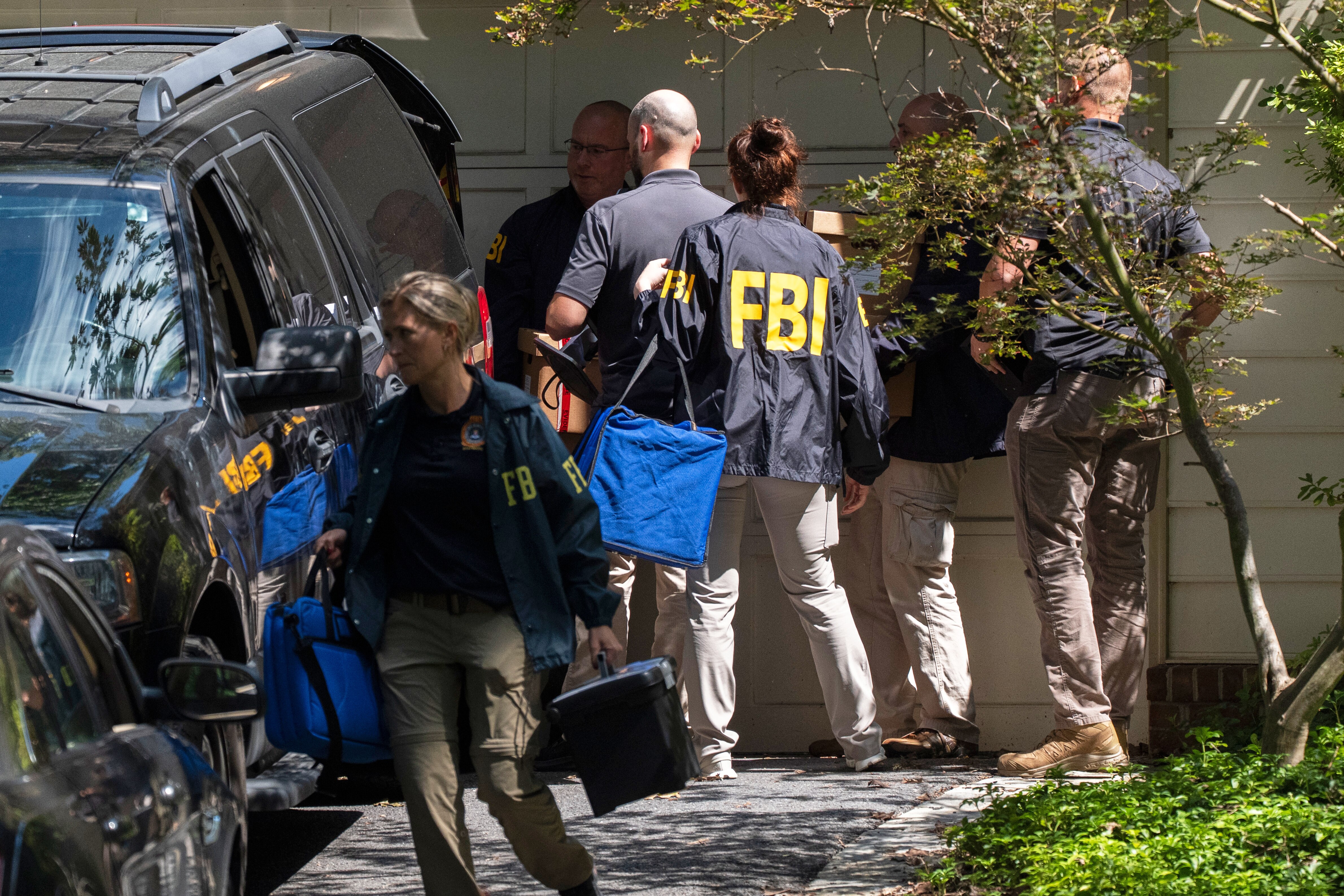 FBI agents carry bags and boxes out of former national security adviser John Bolton's house Friday, Aug. 22, 2025, in Bethesda, Md. (AP Photo/Manuel Balce Ceneta)