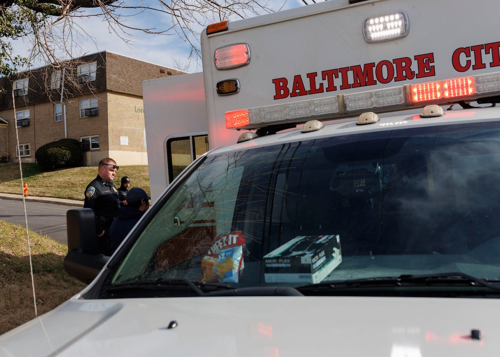 The Baltimore Police Crisis Response Team speaks to an individual receiving medical care on a call.