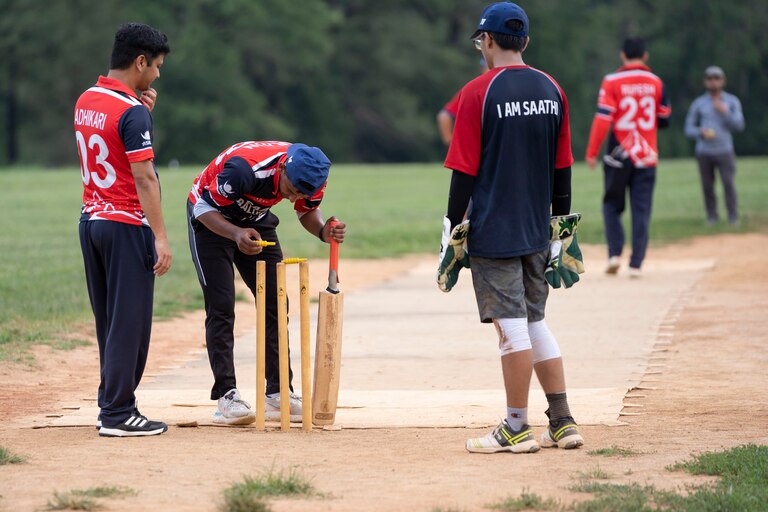A cricket player delicately places a bail on the stumps during practice July 27.