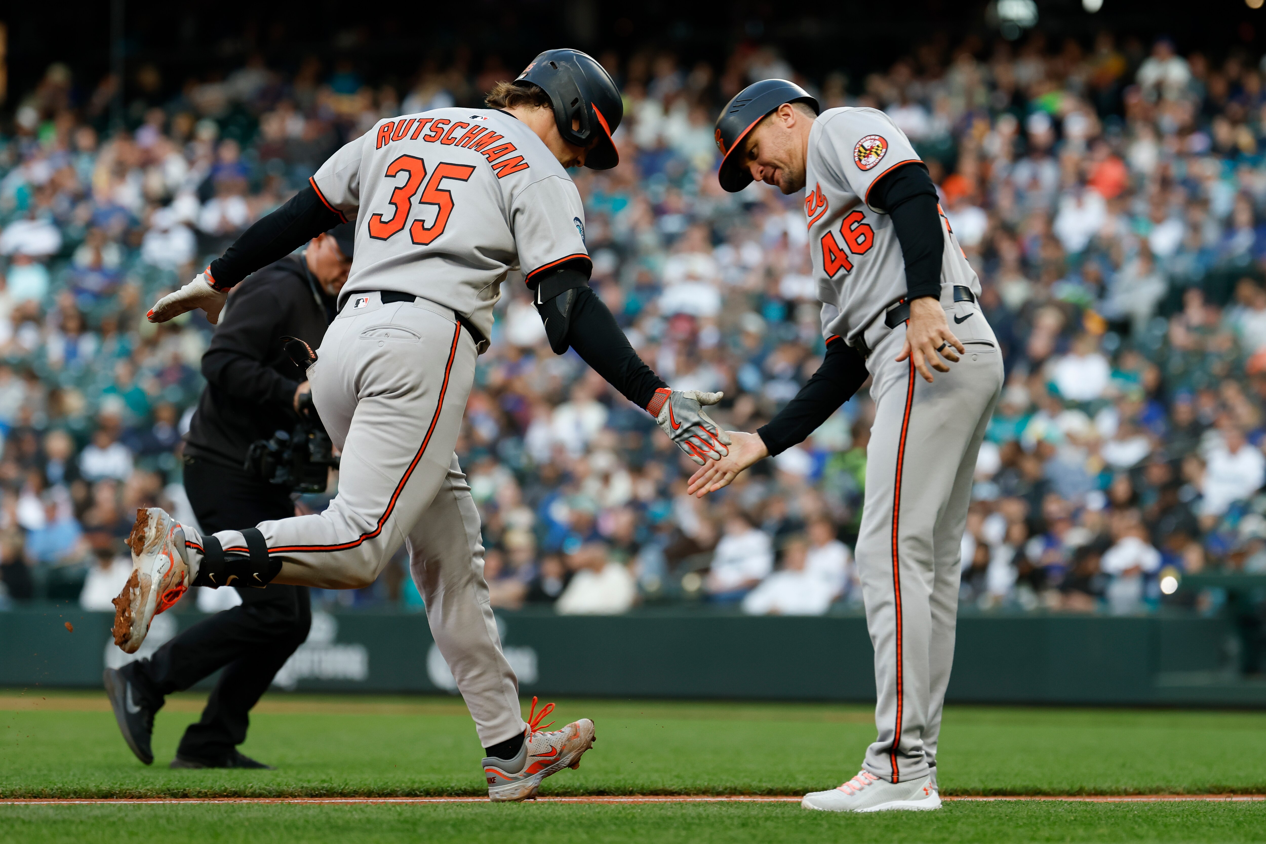 Adley Rutschman accepts congratulations from third base coach Buck Britton as he rounds the bases on his solo home run Wednesday night in Seattle.