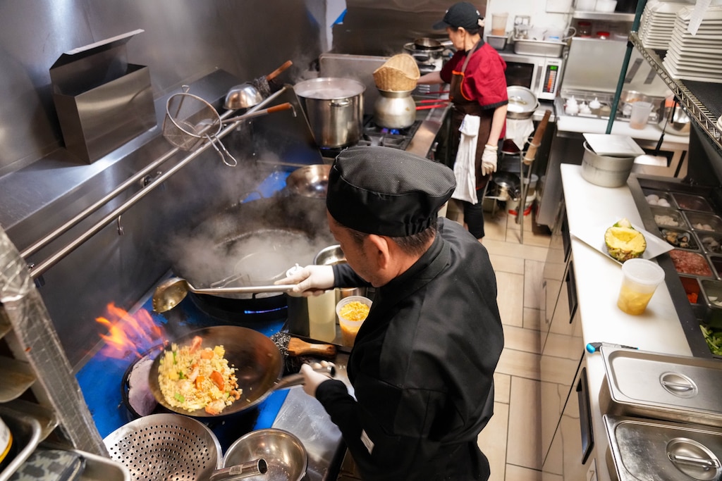 Chef Tim Thammavongsa, front, prepares Pineapple Fried Rice while sous chef Nancy Vongkhamta prepares Lao Sausage in the kitchen of Thai-Lao Garden.