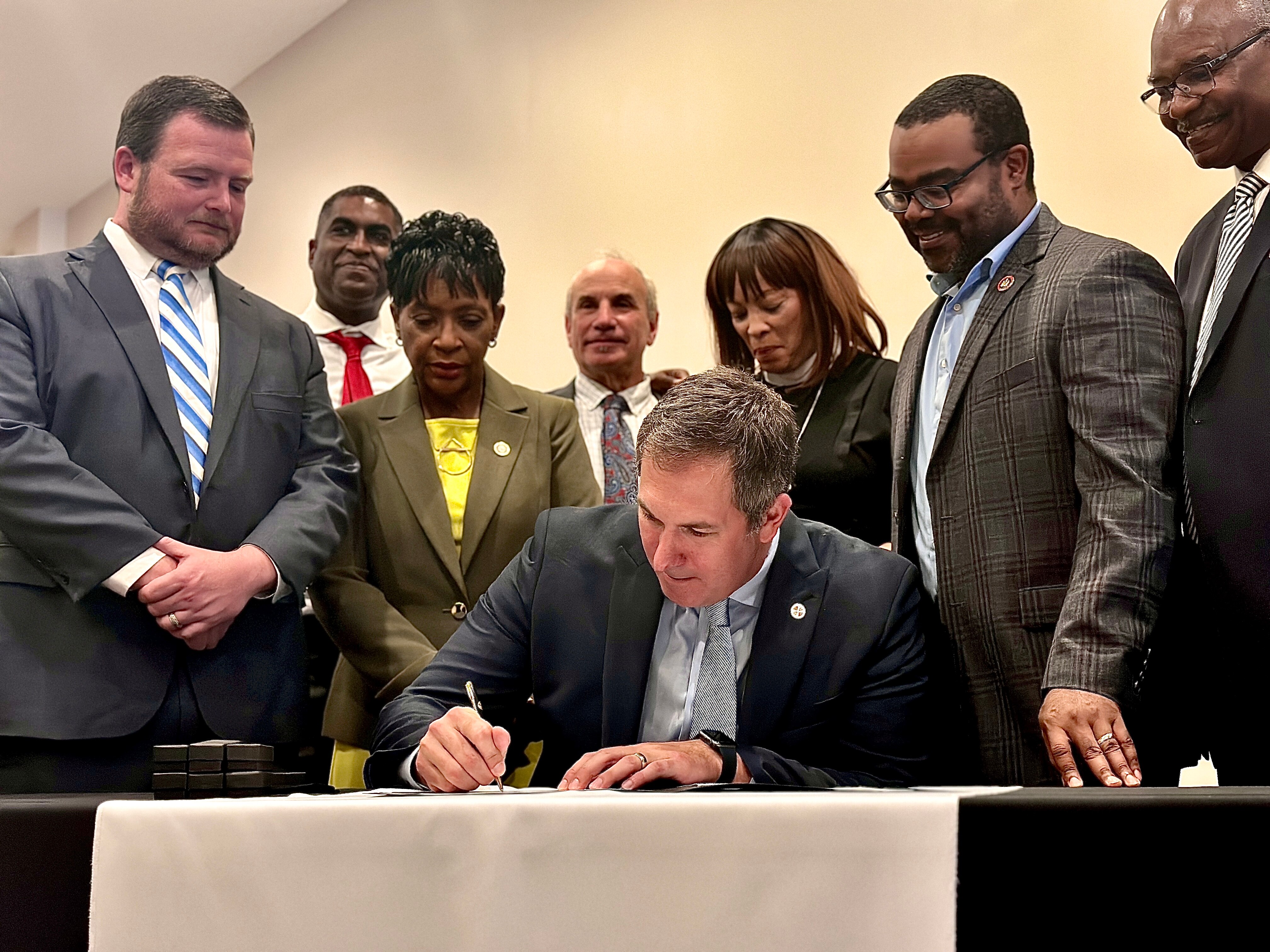 Baltimore County Executive Johnny Olszewski Jr. signs legislation July 13 creating the West Baltimore County Redevelopment Authority, surrounded by: Councilman Patrick "Pat" Young (left), Randallstown NAACP president Ryan Coleman, Maryland House Speaker Adrienne Jones, Councilman Izzy Patoka, Set the Captives Free Outreach Center Pastor Karen Bethea, state Sen. Charles Sydnor, and state Sen. Benjamin Brooks.