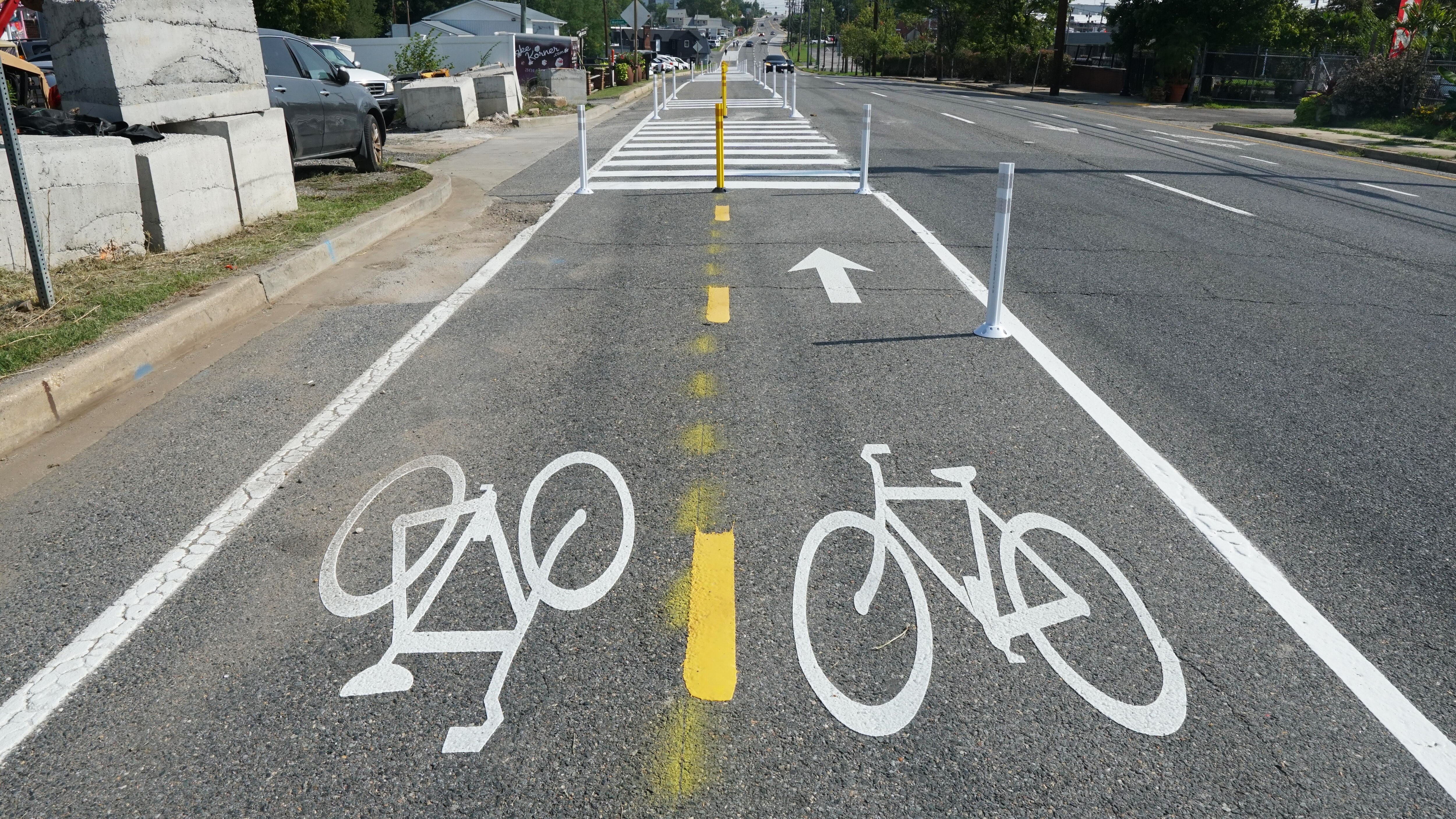 White paint in the shape of two bicycles indicate where a two-way bike path is separated from the rest of the roadway.