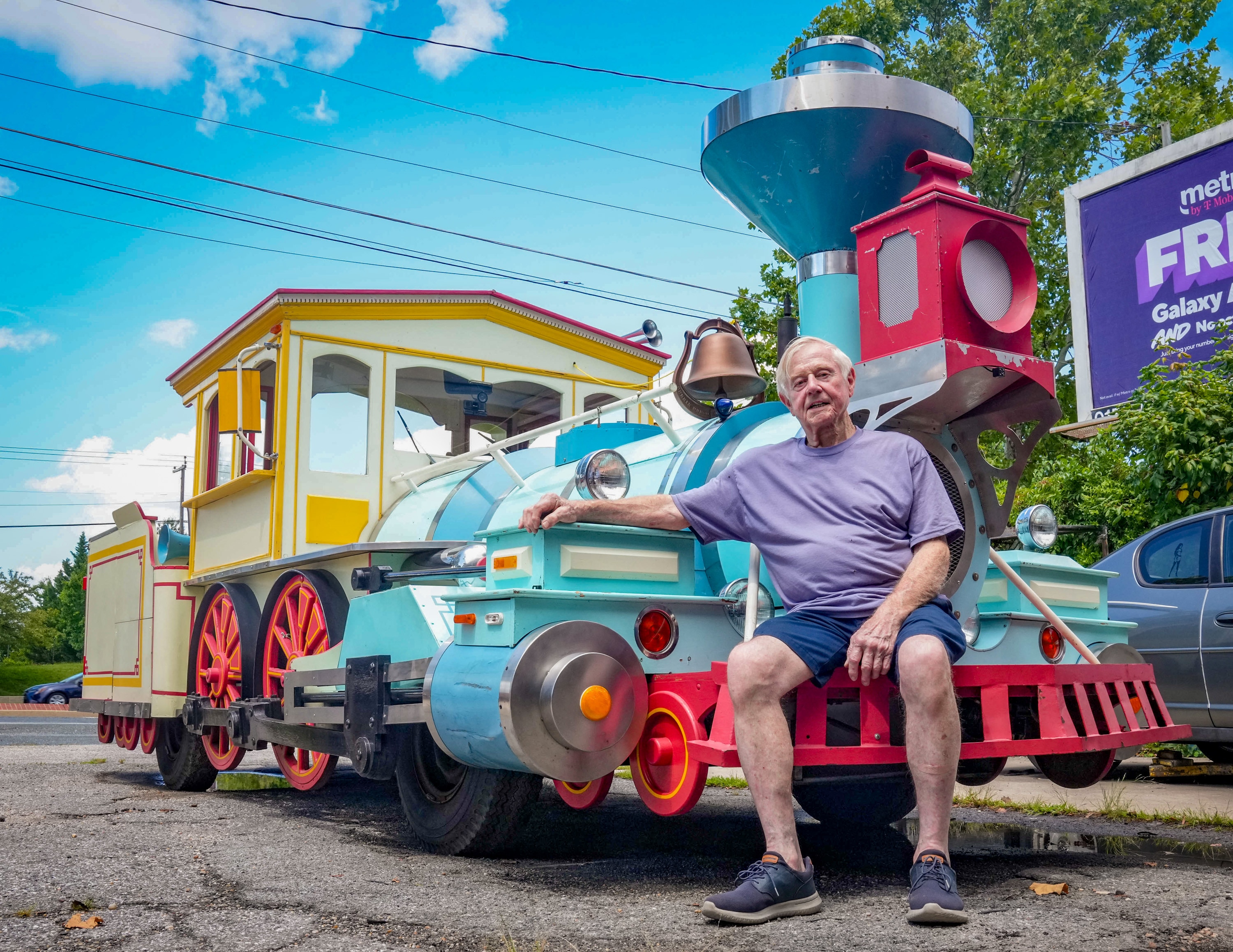 Harry Campbell poses next to his vintage parade train car parked outside his repair shop in Essex.