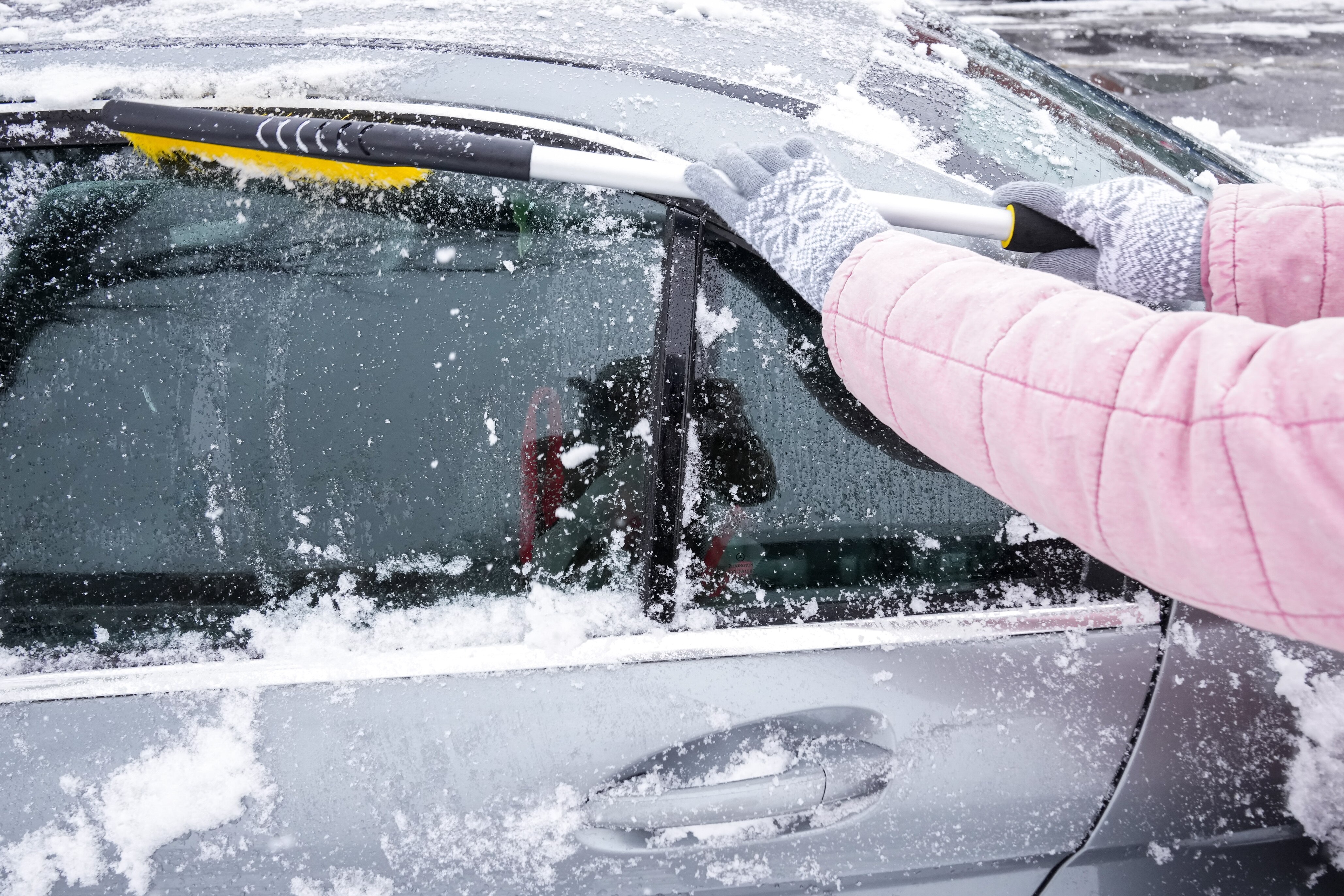 A woman cleans snow off her car on a snowy day in Baltimore on Jan. 19, 2024.