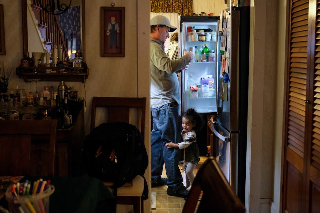 Kyndal Walker hugs the leg of her grandfather, Brian Rannie, in the family’s kitchen.