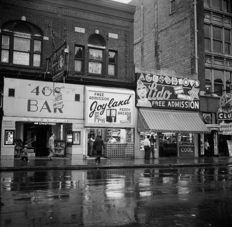 The 408 Bar, Joyland Penny Arcade and Lido amusement hall on 'The Block', a section of East Baltimore Street in Baltimore, Maryland, famous for its adult entertainment venues, 1953.