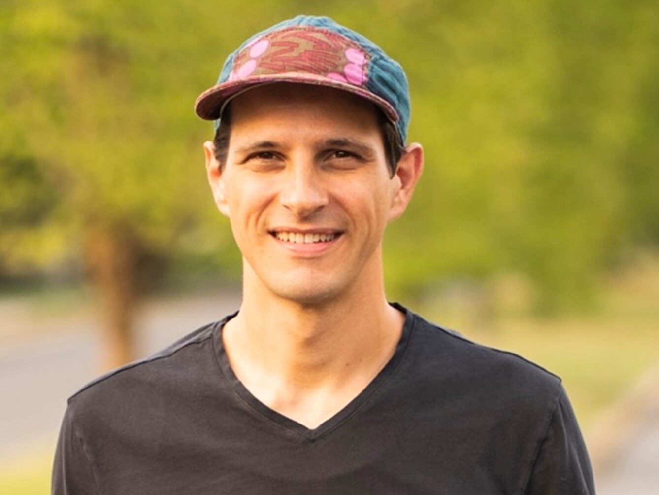 Headshot of City Councilman Ryan Dorsey smiling, wearing a black shirt and multicolored ballcap.