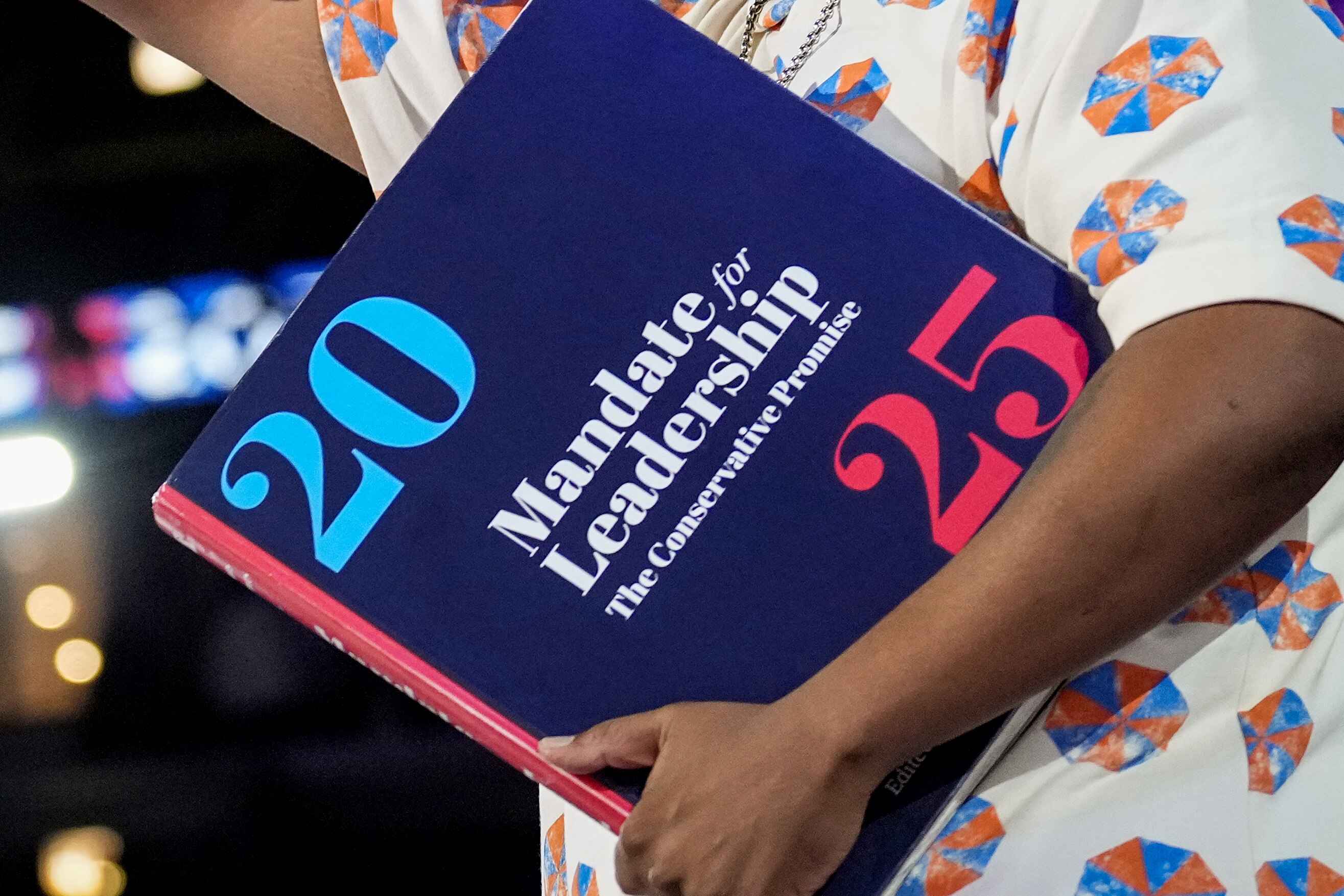 Comedian Kenan Thompson holds a physical copy of Project 2025 on stage during the Democratic National Convention.