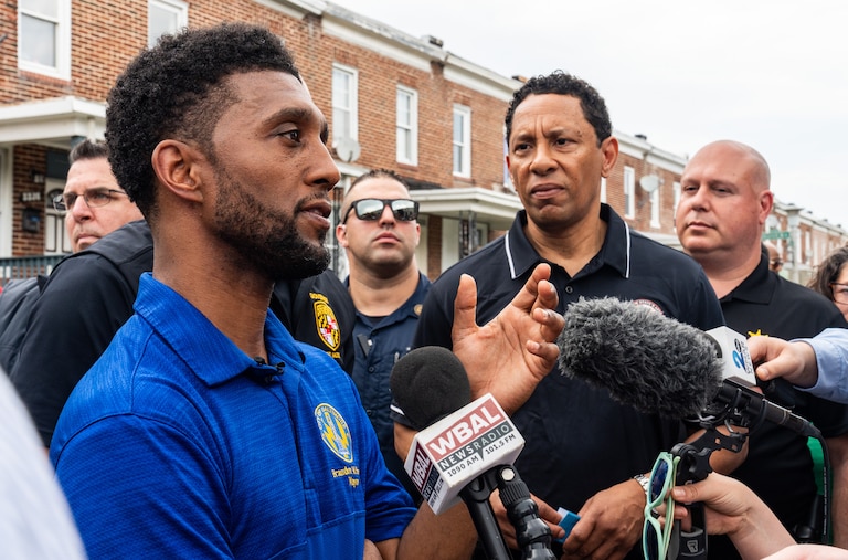 Mayor Brandon Scott, left, speaks to the press as Baltimore City State's Attorney Ivan Bates listens during a community walk through the Four by Four neighborhood on May 7, 2024.