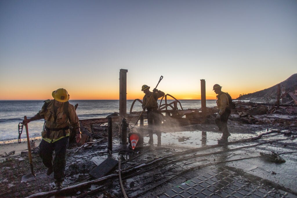 Firefighters try to switch off a fire hydrant in front of a home at Pacific Coast Highway in the Pacific Palisades neighborhood of Los Angeles.