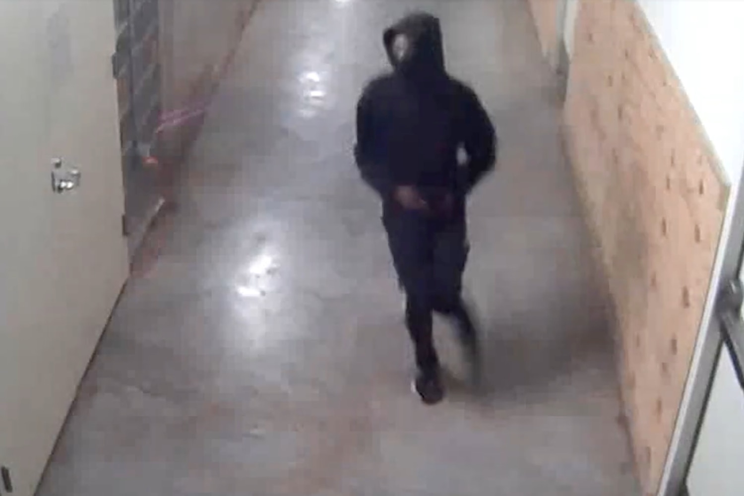 A still image from surveillance video at The Mall in Columbia shows a person in black pants, a black hoodie and a face covering running down a hallway.