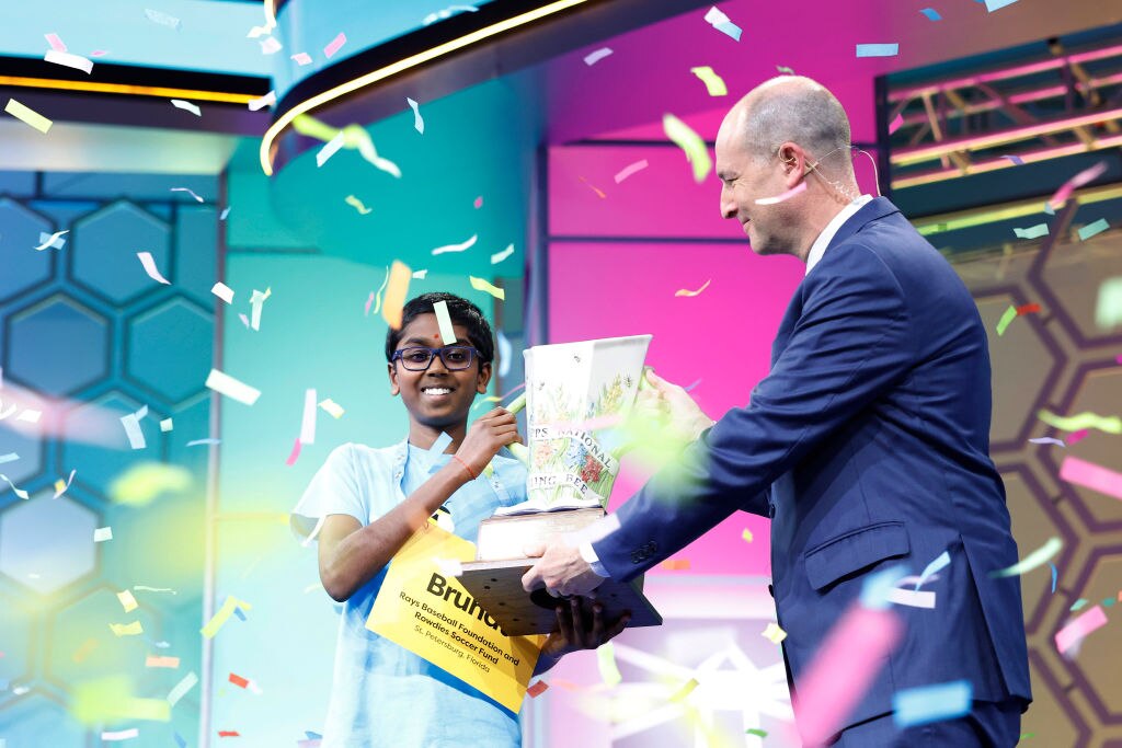 Twelve-year-old Bruhat Soma, of Tampa, Florida, is handed the Scripps Cup after winning the 2024 Scripps National Spelling Bee.