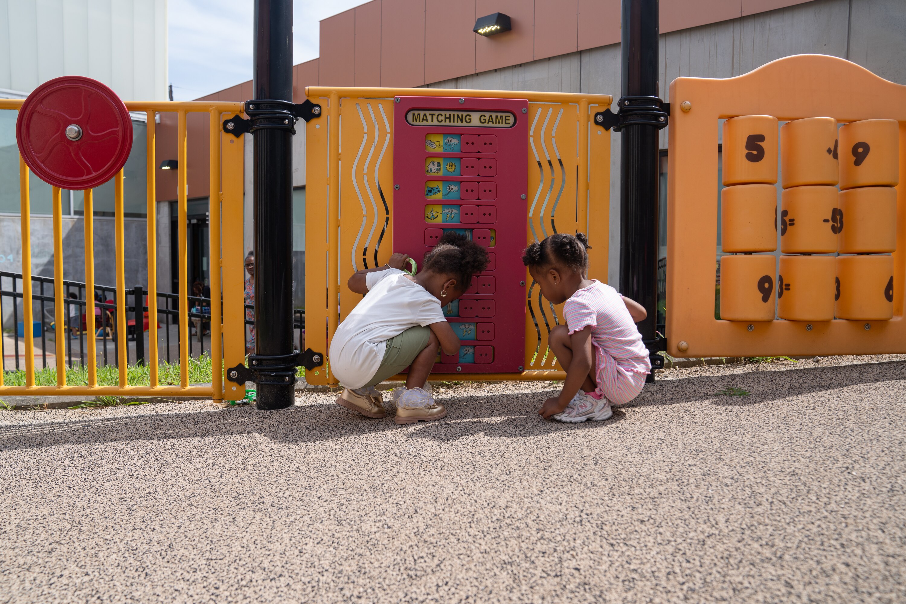 From left, Summer Cummings and Jade Waldron play a matching game together on a playground in Baltimore City.
