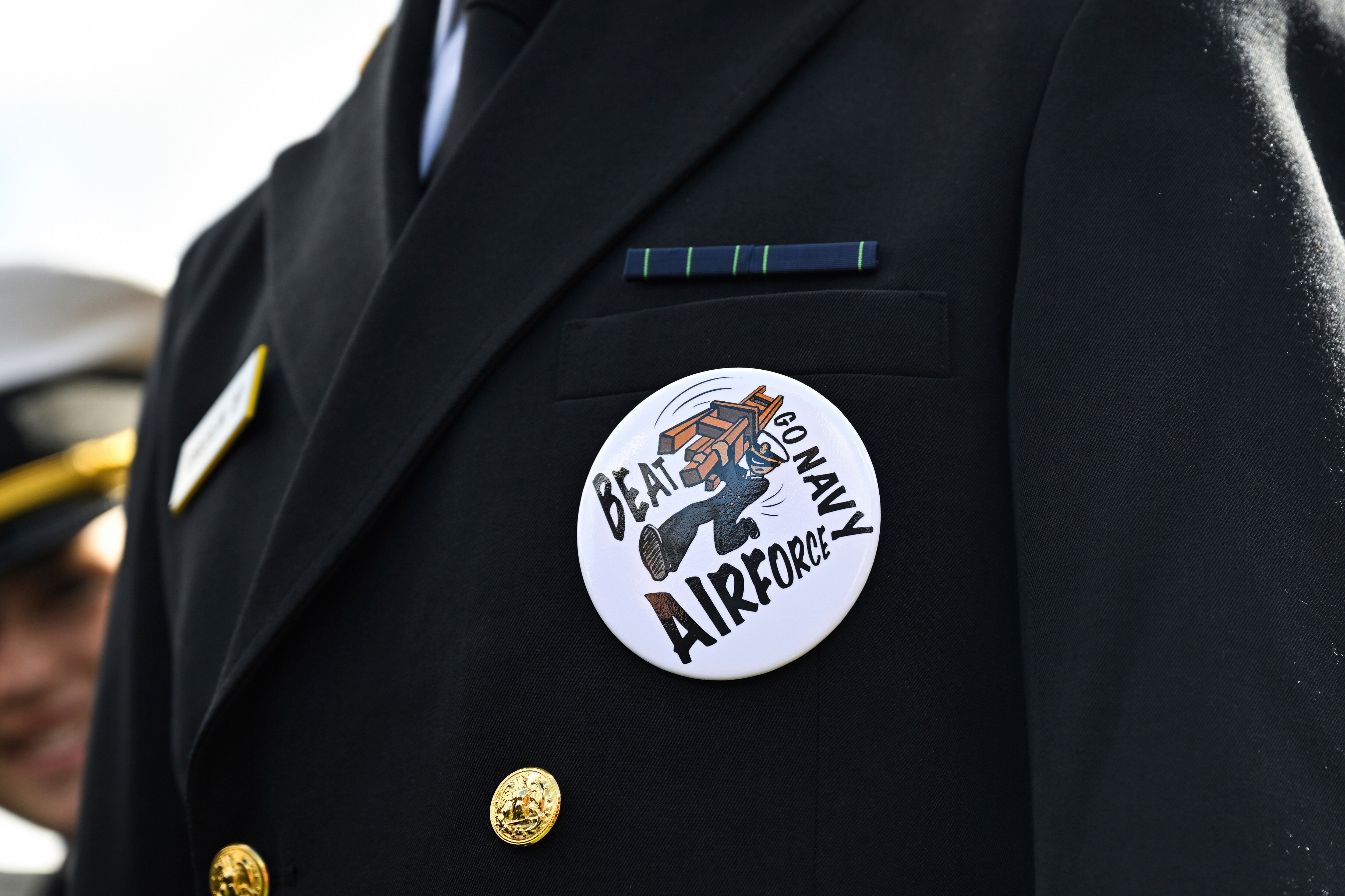 FILE - A Midshipmen is seen wearing a pin that says 'Beat Air Force Go Navy' before an NCAA college football game, Oct. 21, 2023, in Annapolis. (AP Photo/Terrance Williams, file)