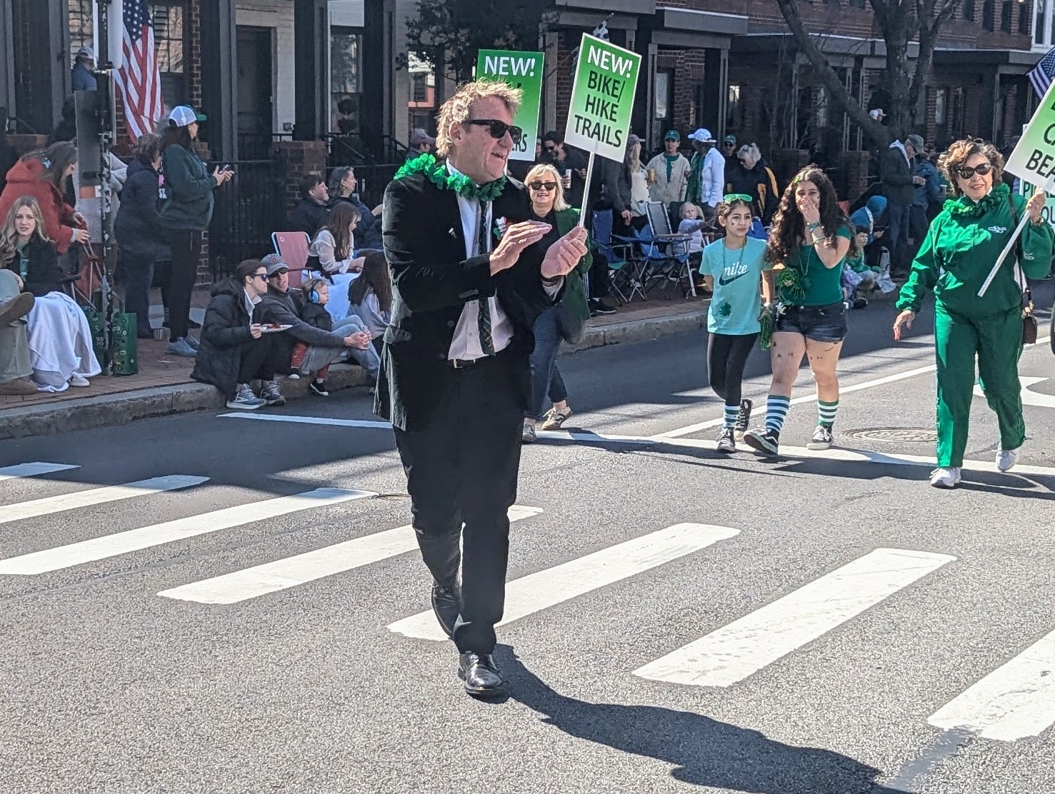 Annapolis Mayor Gavin Buckley marches in the St. Patrick's Parade on March 9, 2025, with supporters holding up signs listing his accomplishments.