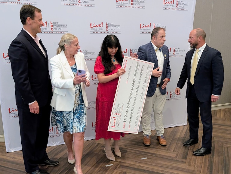 Lauren Garrett, center, adjusts the giant fake check the BWI Community Development Foundation received for $1.5 million at the annual Local Development Council grants luncheon.