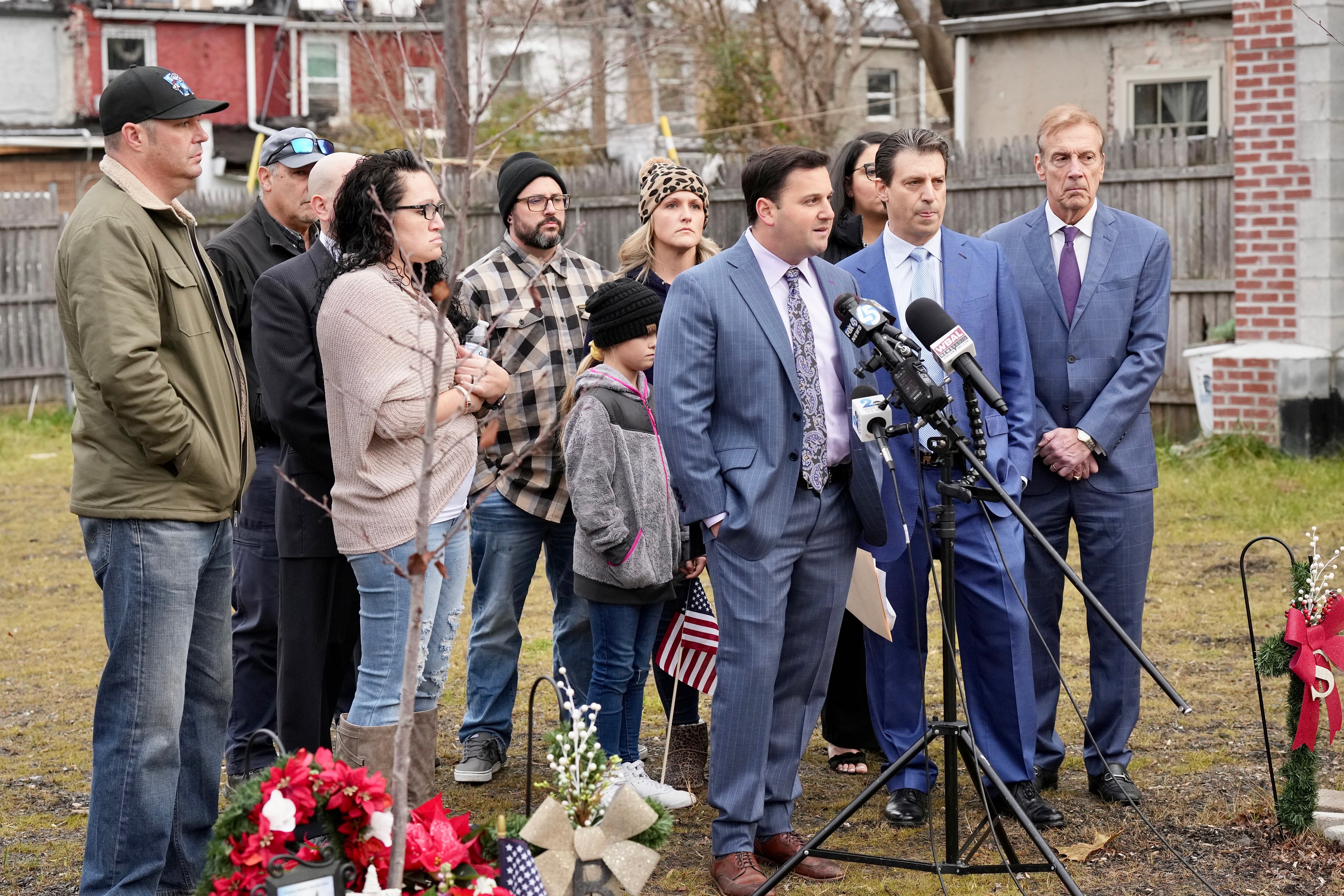 Photo of the familiese of Lt. Paul Butrim, Lt. Kelesy Sadler FF/PM Kenneth Lacayo with their attorneys t the Stricker street fire memorials.