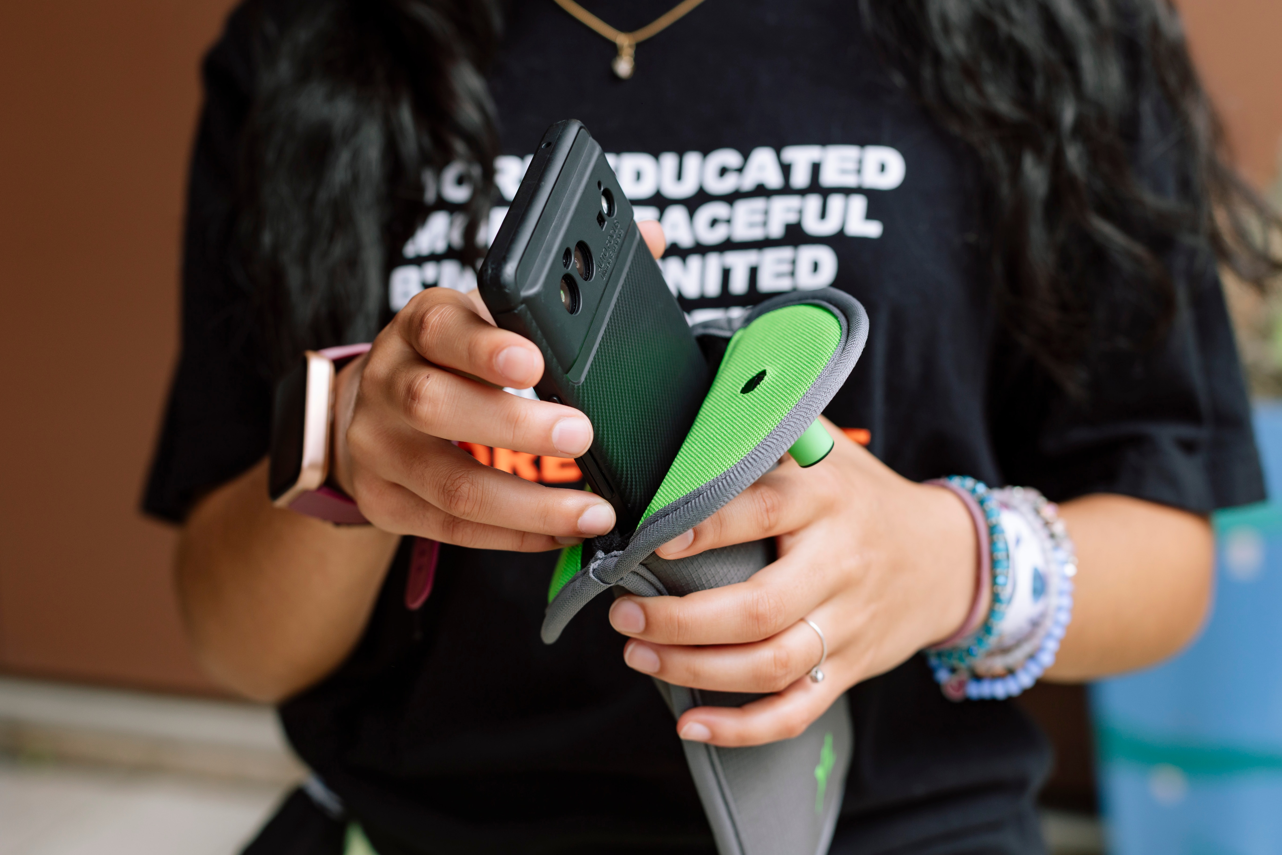 Eighth grader Bria Shah slides a cellphone into a Yondr pouch, a device Hampstead Hill Academy uses to lock up students’ phones during the school day.