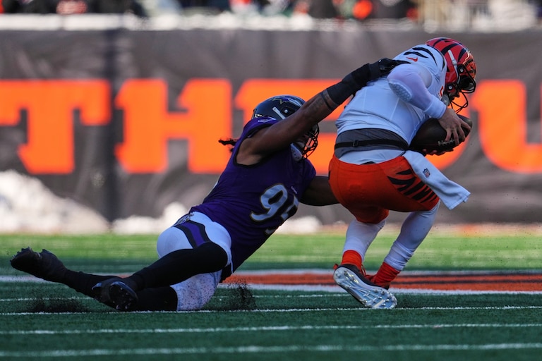 Cincinnati Bengals quarterback Joe Burrow, right, is sacked by Baltimore Ravens linebacker Tavius Robinson (95) during the first half.