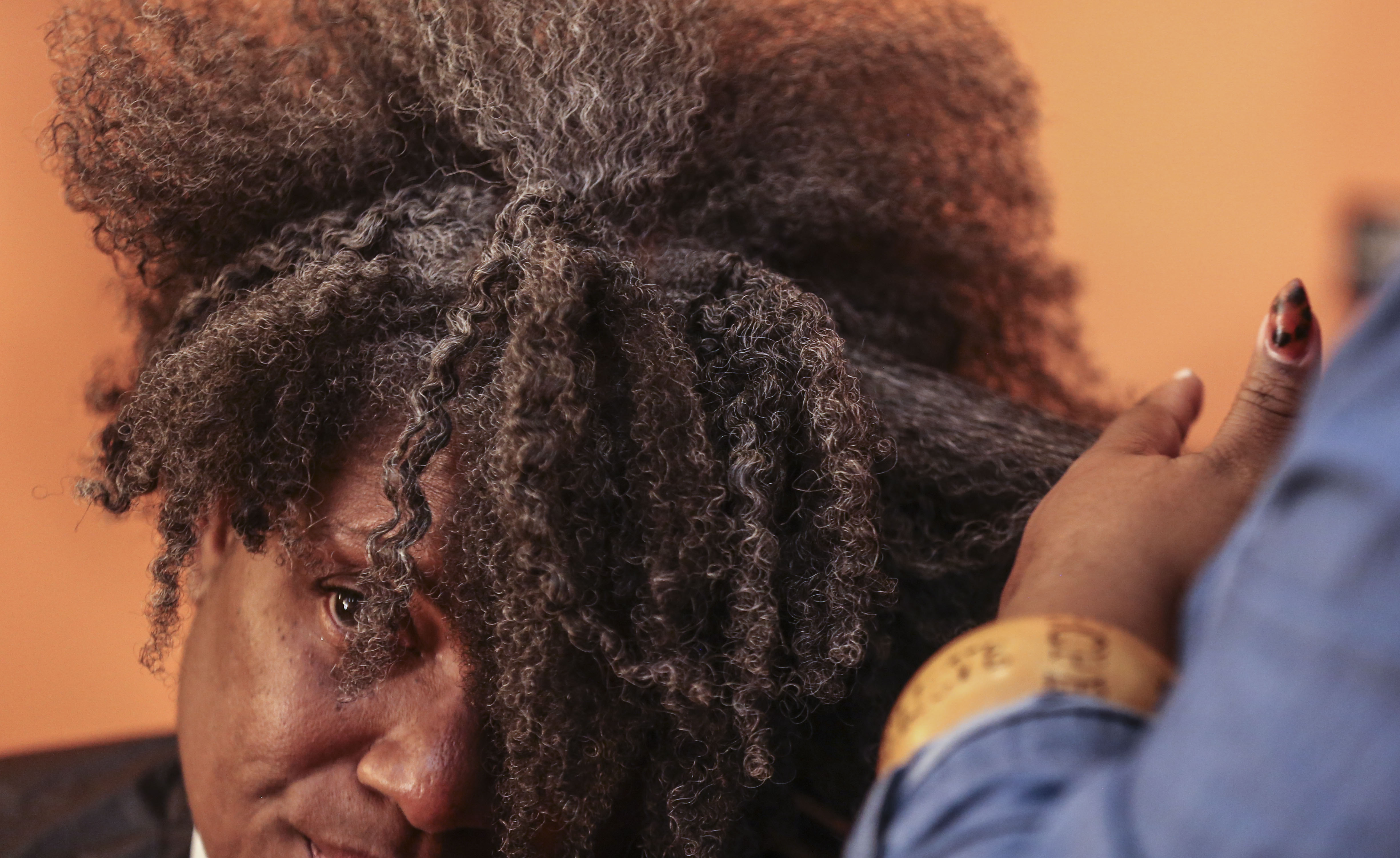 Stylist Ericka Cherrie styles Torre McKiver’s hair working with her natural texture. Cherrie says she has seen an uptick in clients requesting more natural hairstyles since the Crown Act was passed.