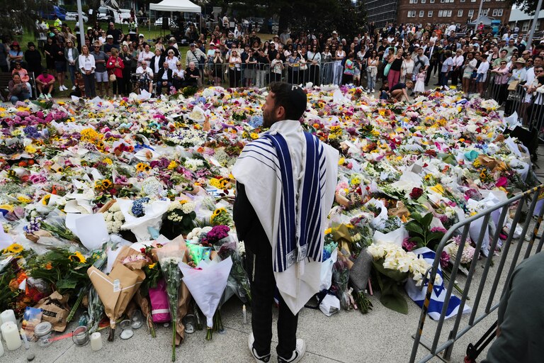 Rabbi Yossi Friedman speaks to people gathering at a flower memorial by the Bondi Pavilion at Bondi Beach on Tuesday, Dec. 16, 2025, following Sunday's shooting in Sydney, Australia. (AP Photo/Mark Baker)
