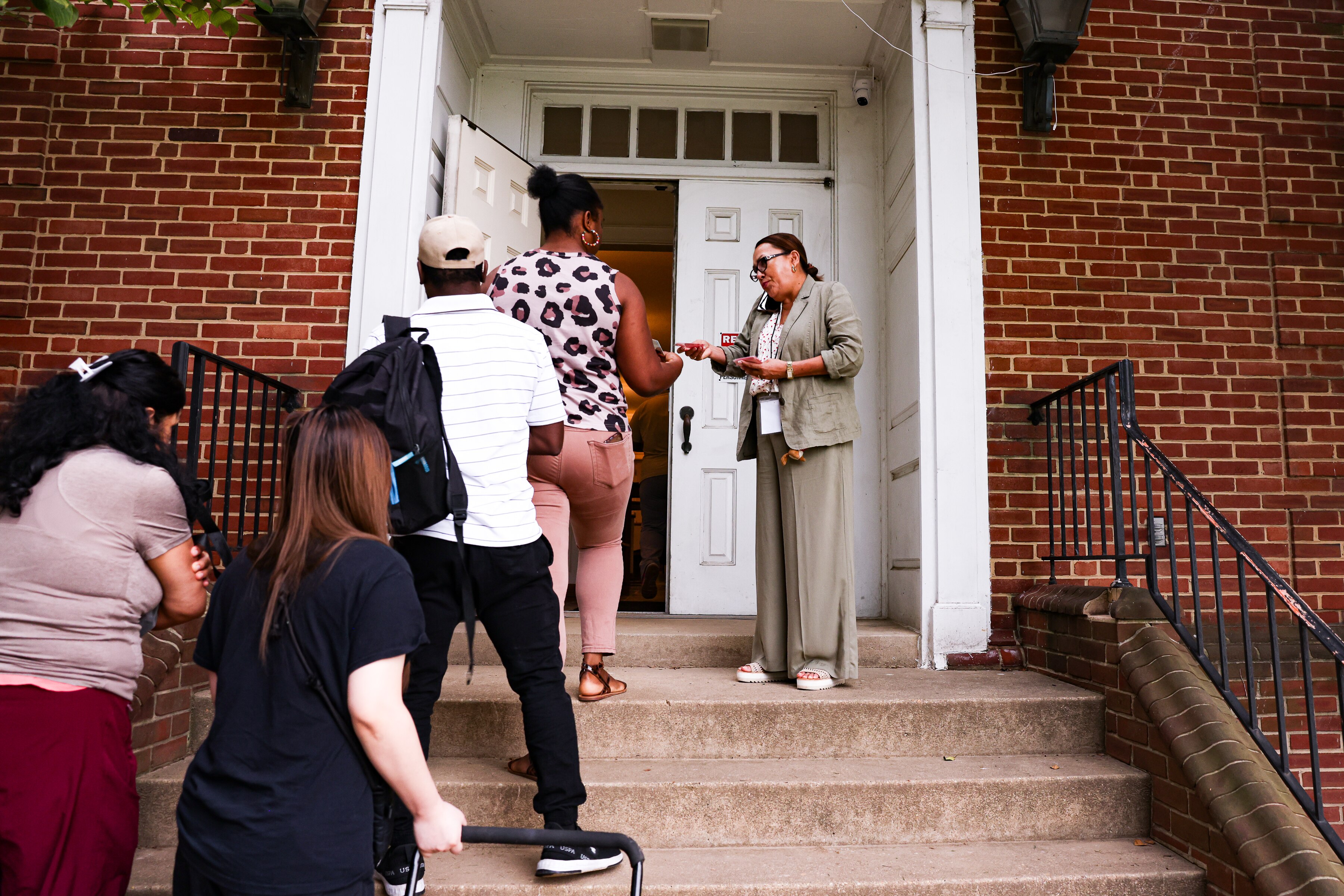 Rev. Diana Wingeier-Rayo hands out numbered cards to people arriving for a weekly food distribution event at Hughes United Methodist Church in Wheaton earlier this month.