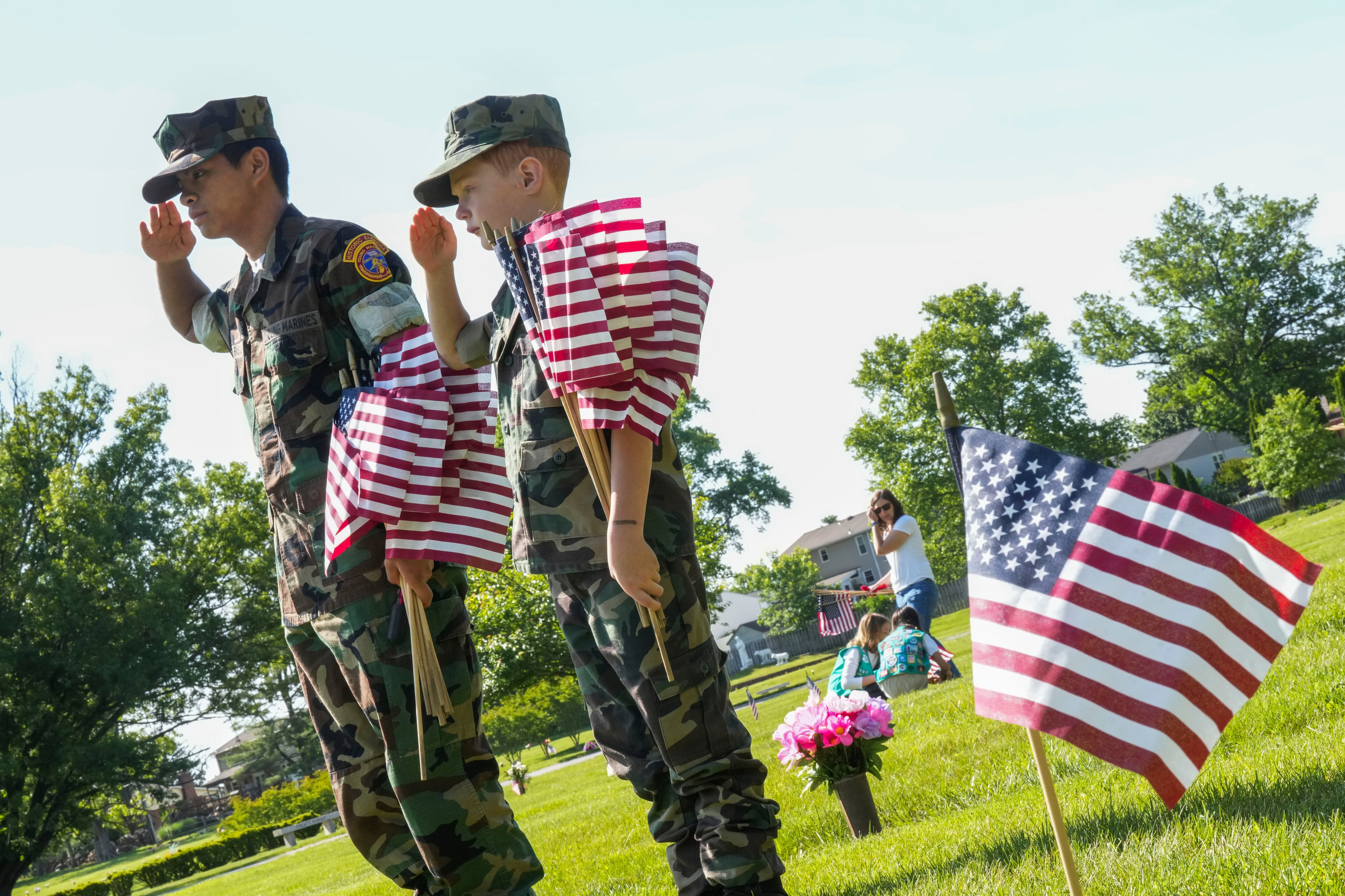 Young Marine Gunnery Sergeant Colin Farias, 16, and Private Duffy, 8, plant flags on gravesites at Dulaney Valley Memorial Gardens on May 27, 2023.