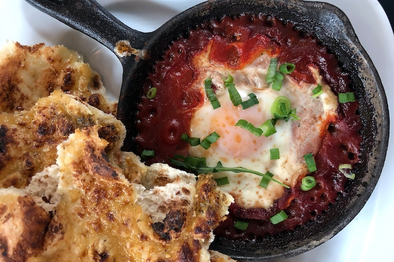 Gunther & Co. serves its shakshouka in a skillet with a spiced tomato base and flatbread.