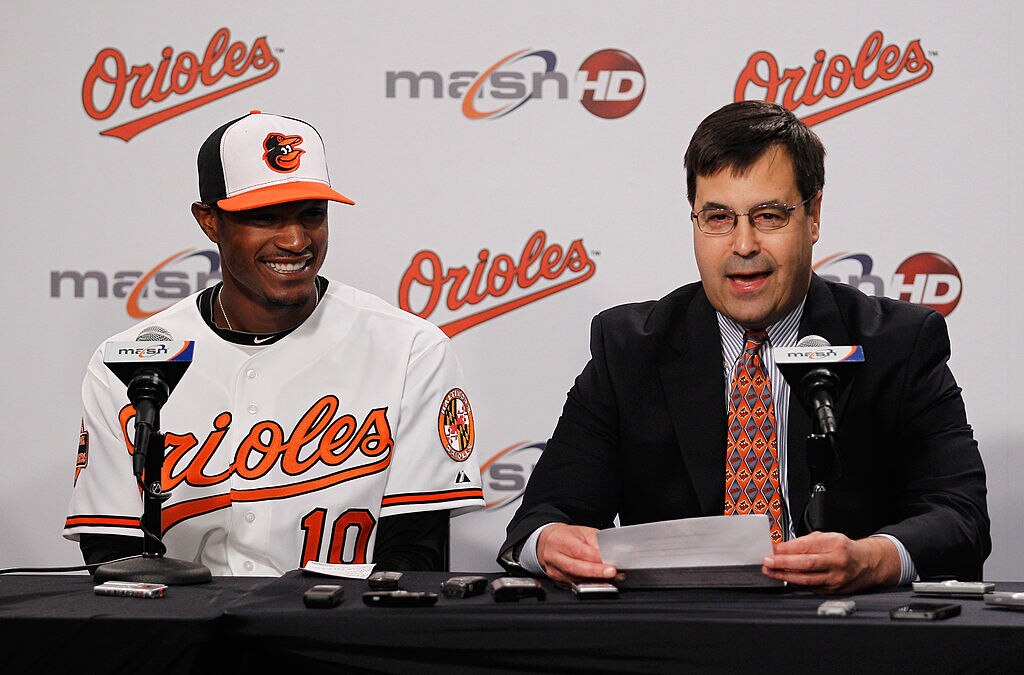 BALTIMORE, MD - MAY 27:  Adam Jones #10 of the Baltimore Orioles smiles while addressing the media with Dan Duquette, executive vice president of baseball operations for the team after announcing Jones had signed a six-year contract through the 2018 season before the start of the Orioles game against the Kansas City Royals at Oriole Park at Camden Yards on May 27, 2012 in Baltimore, Maryland.