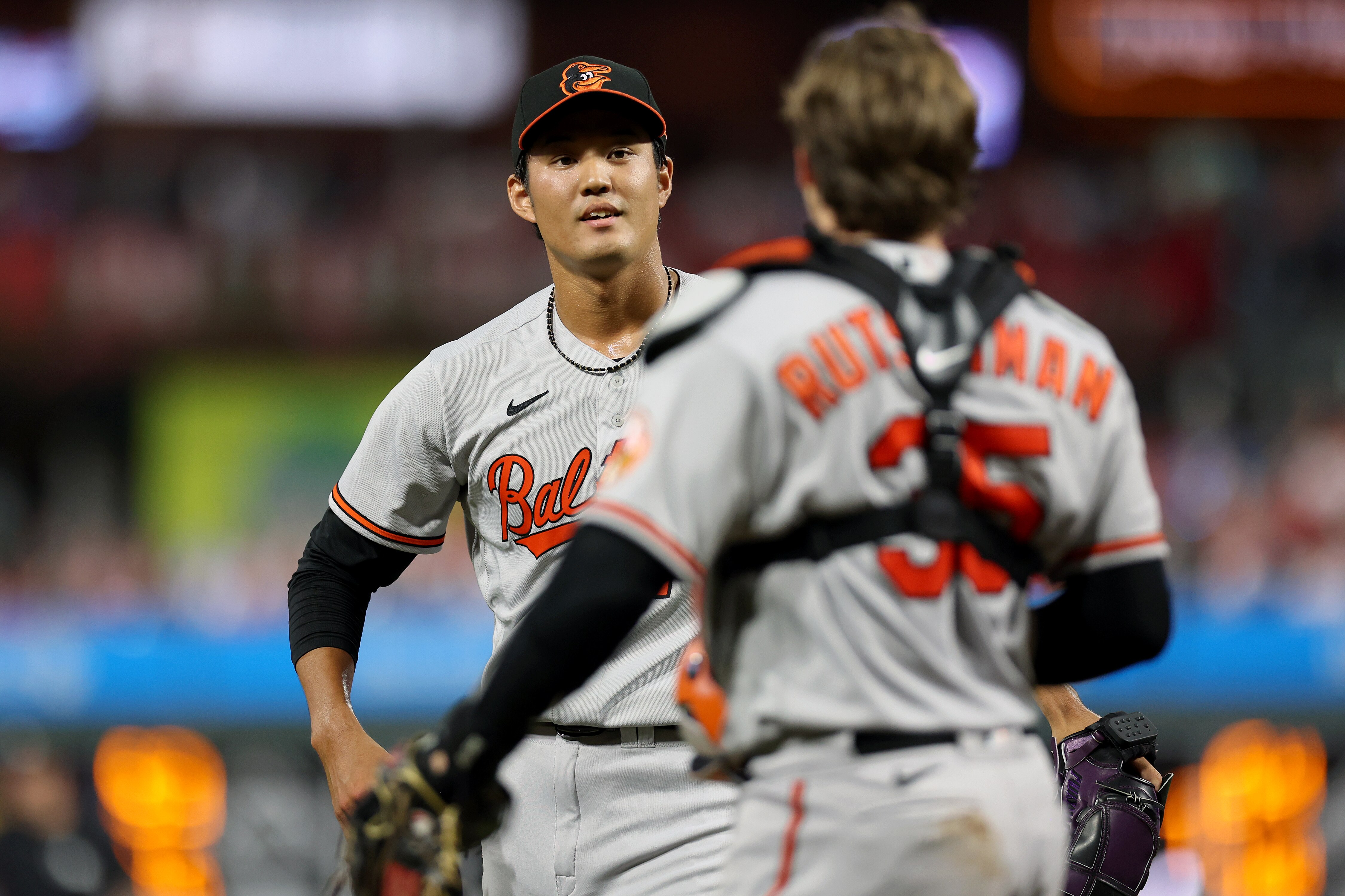 Orioles reliever Shintaro Fujinami welcomes catcher Adley Rutschman to the mound last week in Philadelphia. Fujinami says he wants to learn English instead of using a translator.