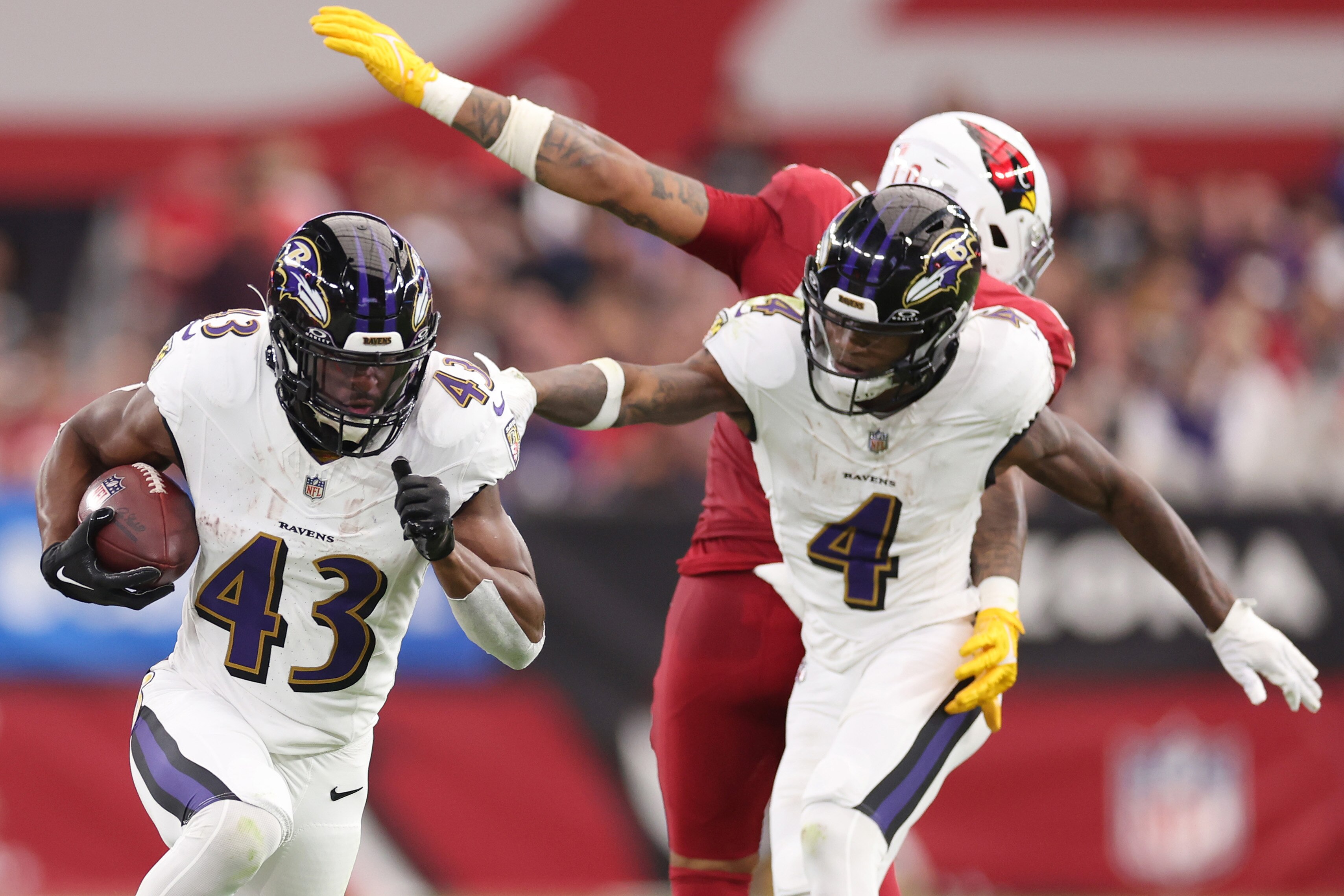 GLENDALE, ARIZONA - OCTOBER 29: Justice Hill #43 of the Baltimore Ravens runs the ball while Zay Flowers #4 blocks Josh Woods #10 of the Arizona Cardinals during the second quarter at State Farm Stadium on Oct. 29, 2023, in Glendale, Arizona.