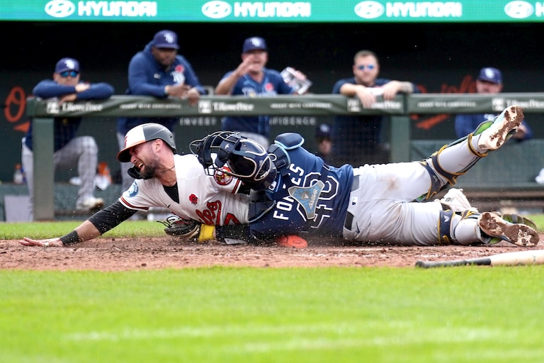 Baltimore Orioles outfielder Colton Cowser narrowly beats Tampa Bay Rays catcher Forbes to home plate as he slides to safety in the 12th inning. The call was initially that he was out but it was overturned by officials after a lengthy replay.