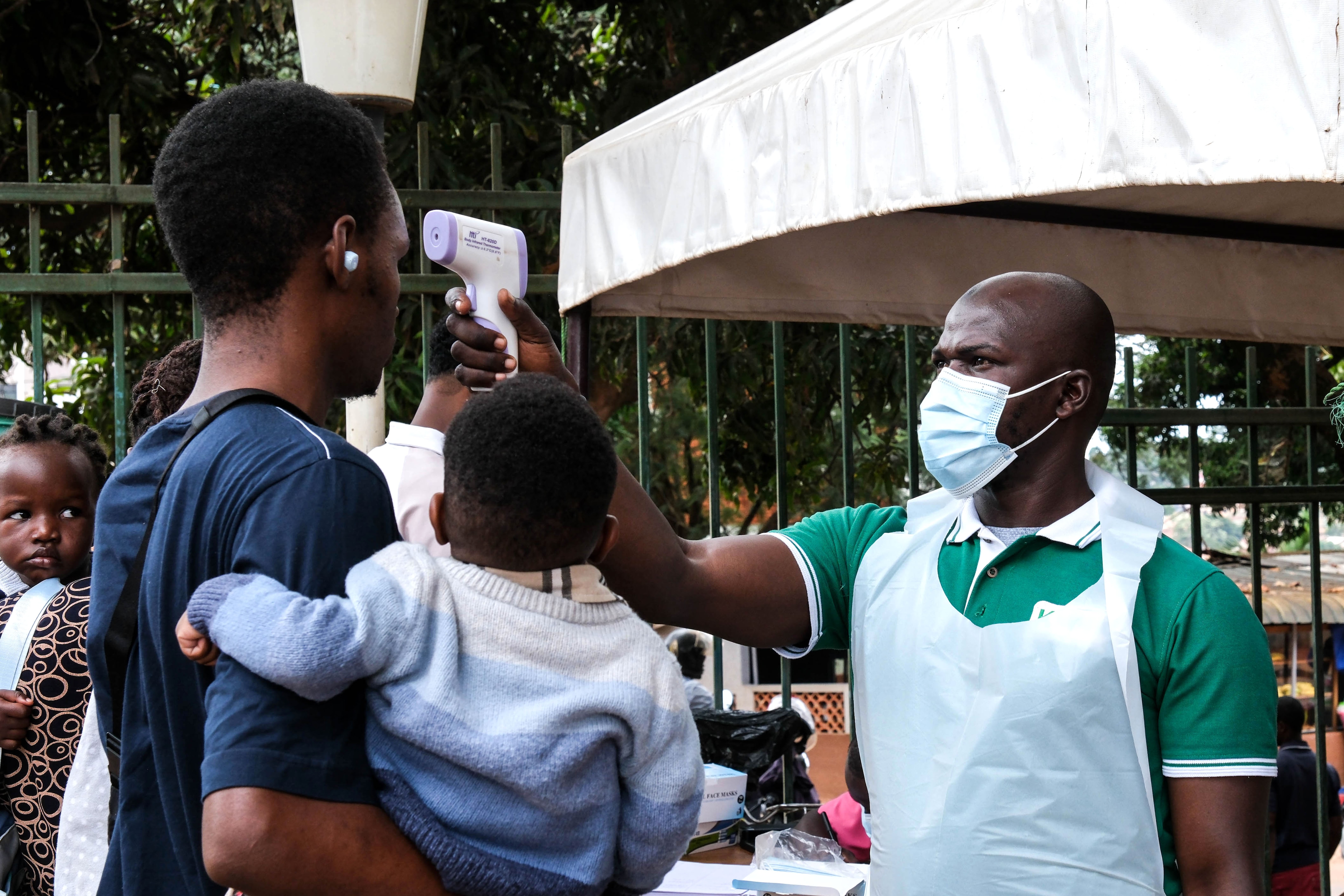 A health official uses a thermometer to screen people in front of Kibuli Muslim Hospital in Kampala, Uganda, Saturday, May 16, 2026. (AP Photo/ Hajarah Nalwadda)